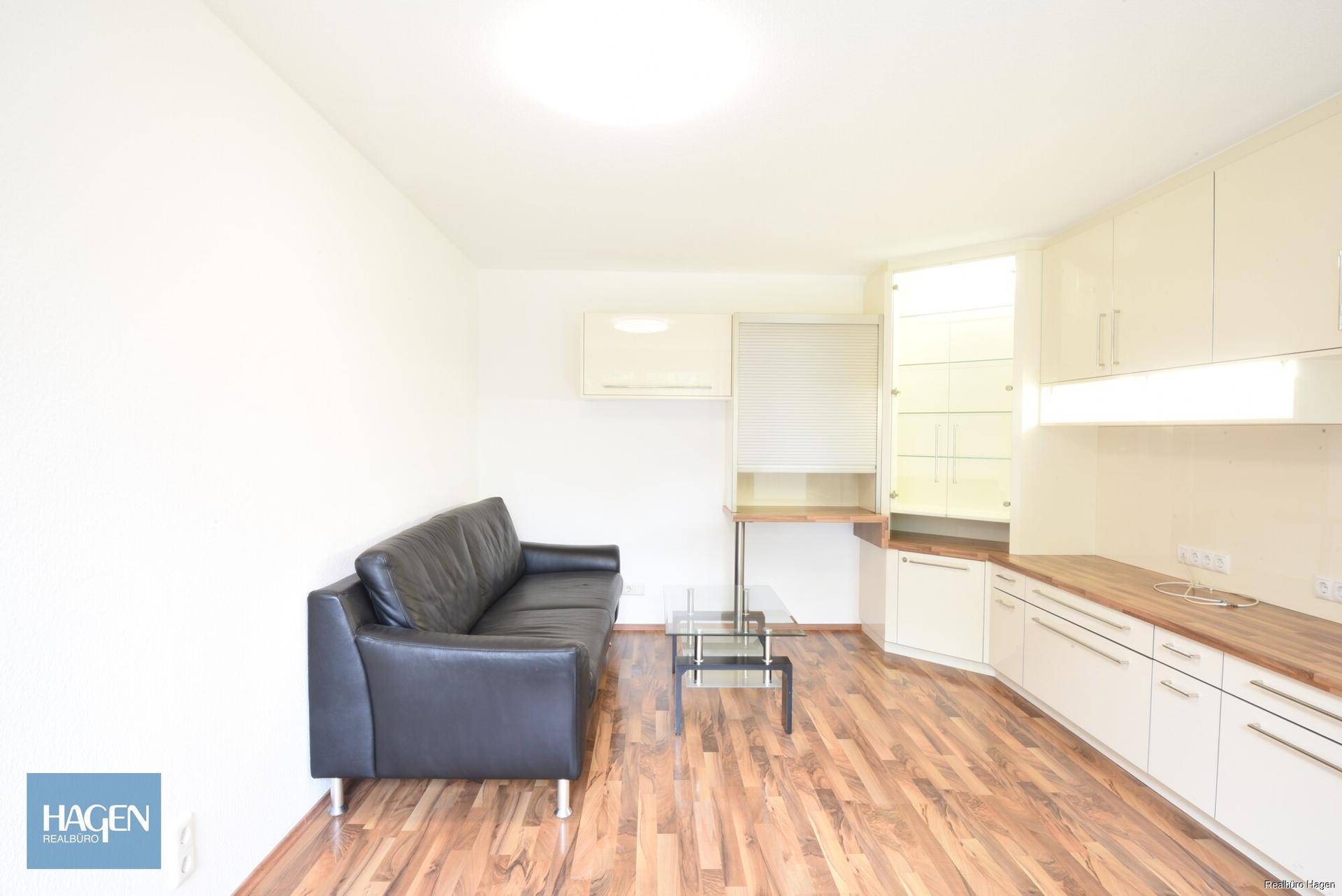 Gemütliches Wohnzimmer mit Sofa, Holzboden und praktischen Einbauschränken.