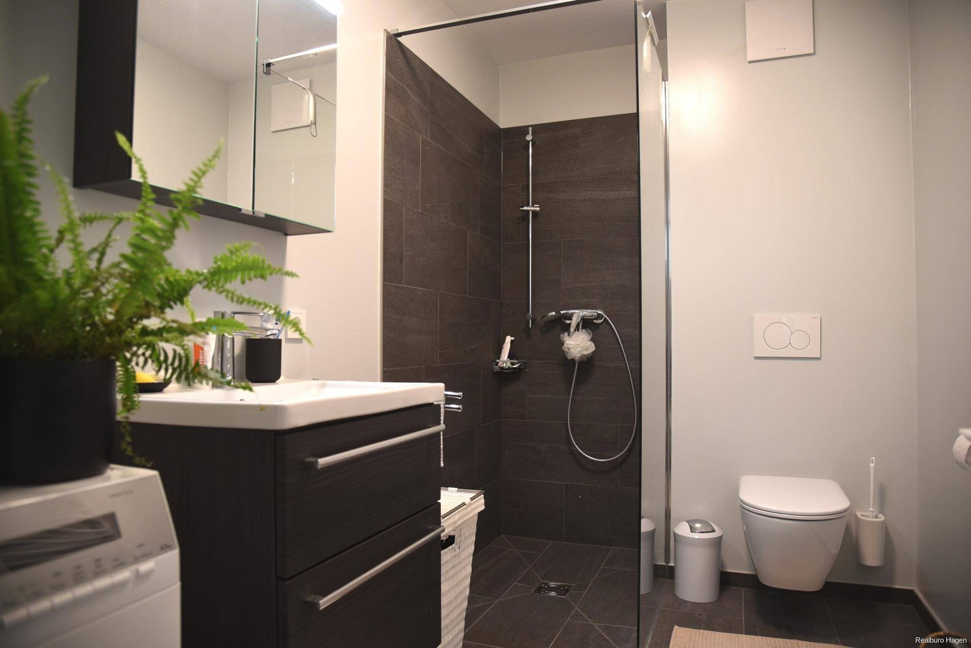 Modernes Badezimmer mit ebenerdiger Dusche, wandhängendem WC und Waschbeckenunterschrank.