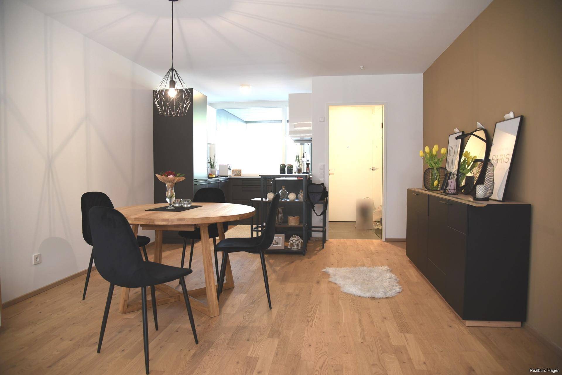 Offener Wohn- und Essbereich mit Blick auf die moderne Küche und Holzboden.