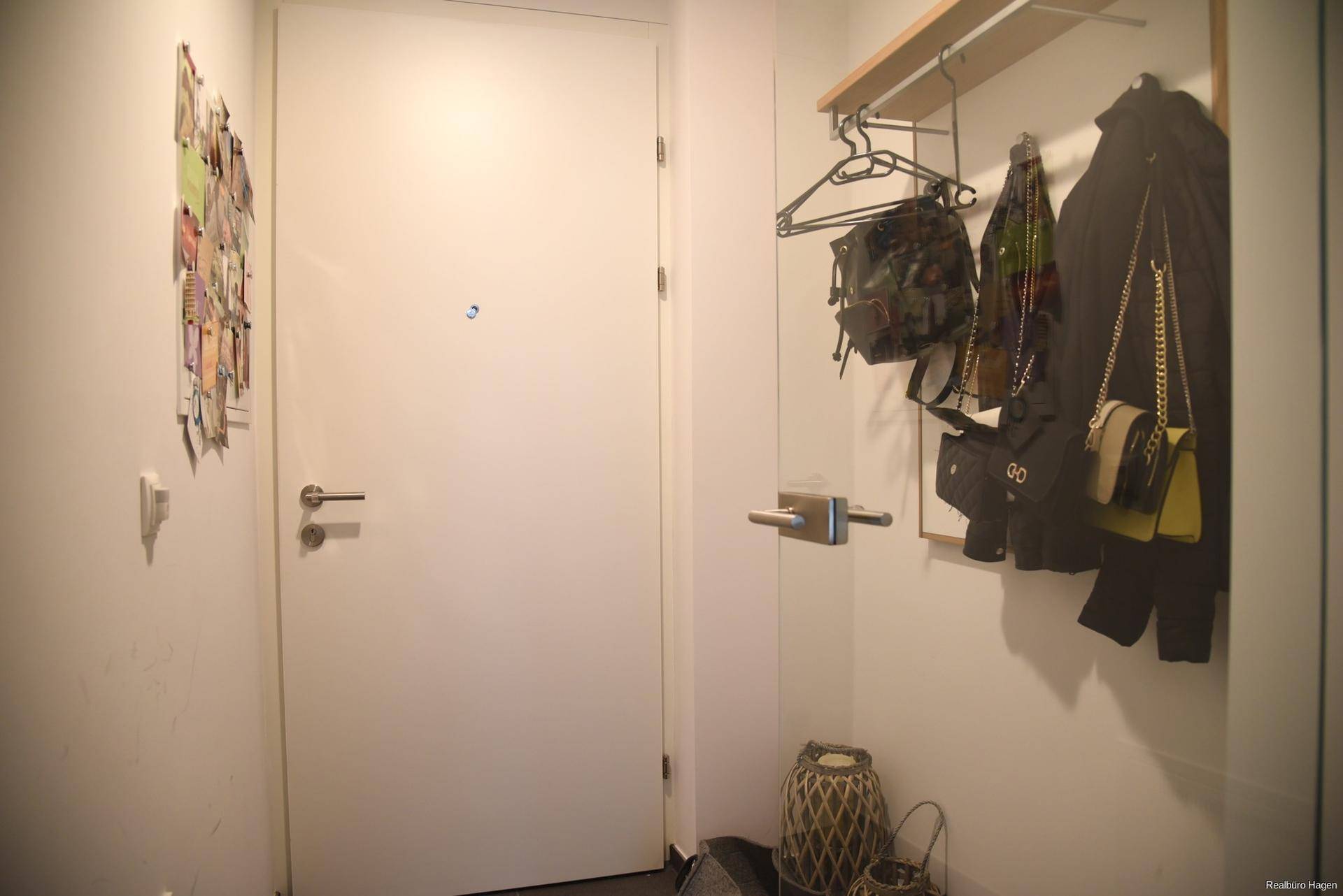 Eingangsbereich mit Garderobe und weißer Tür, bietet Platz für persönliche Gegenstände.