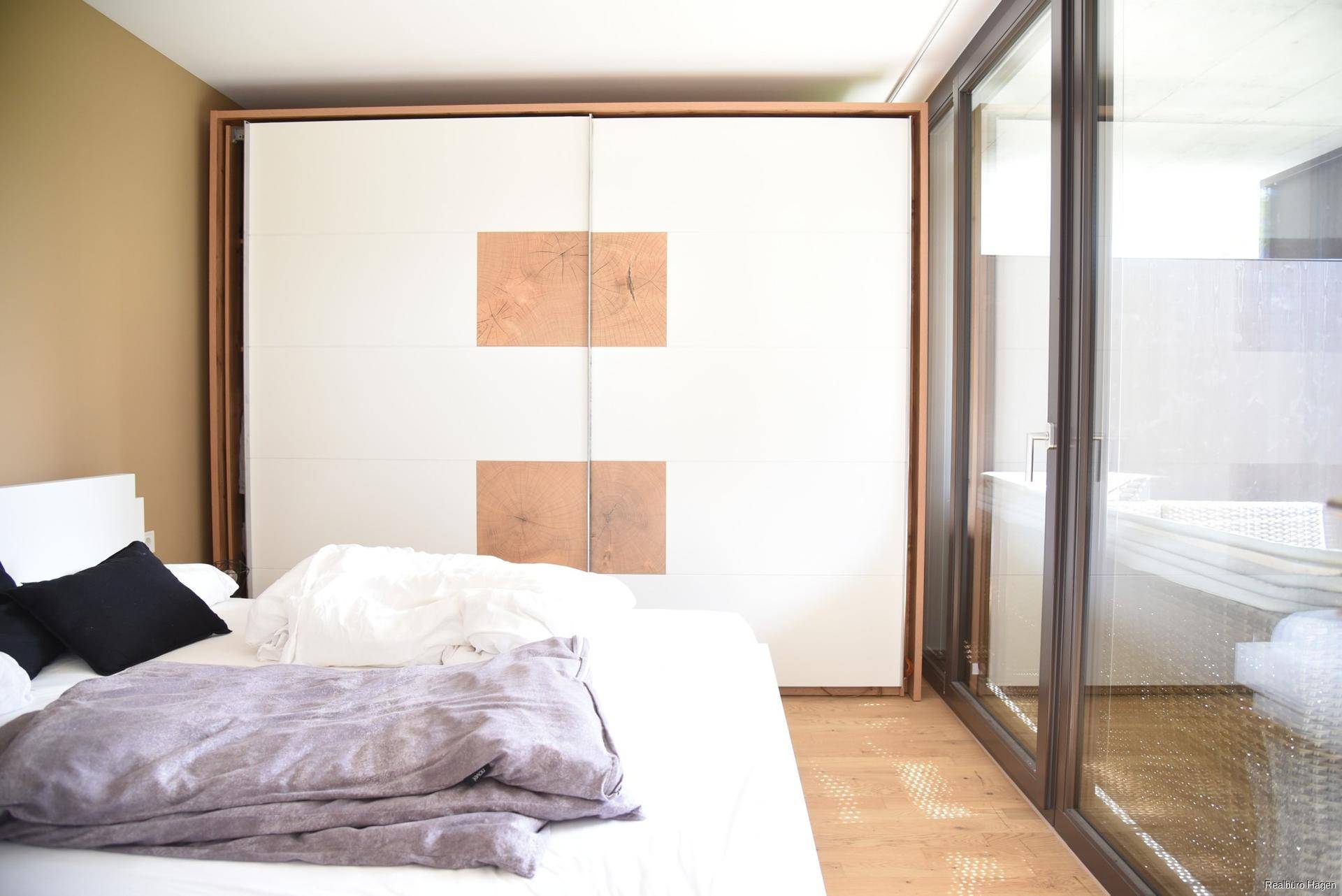 Schlafzimmer mit großem Kleiderschrank, Holzboden und direktem Zugang zur Terrasse.