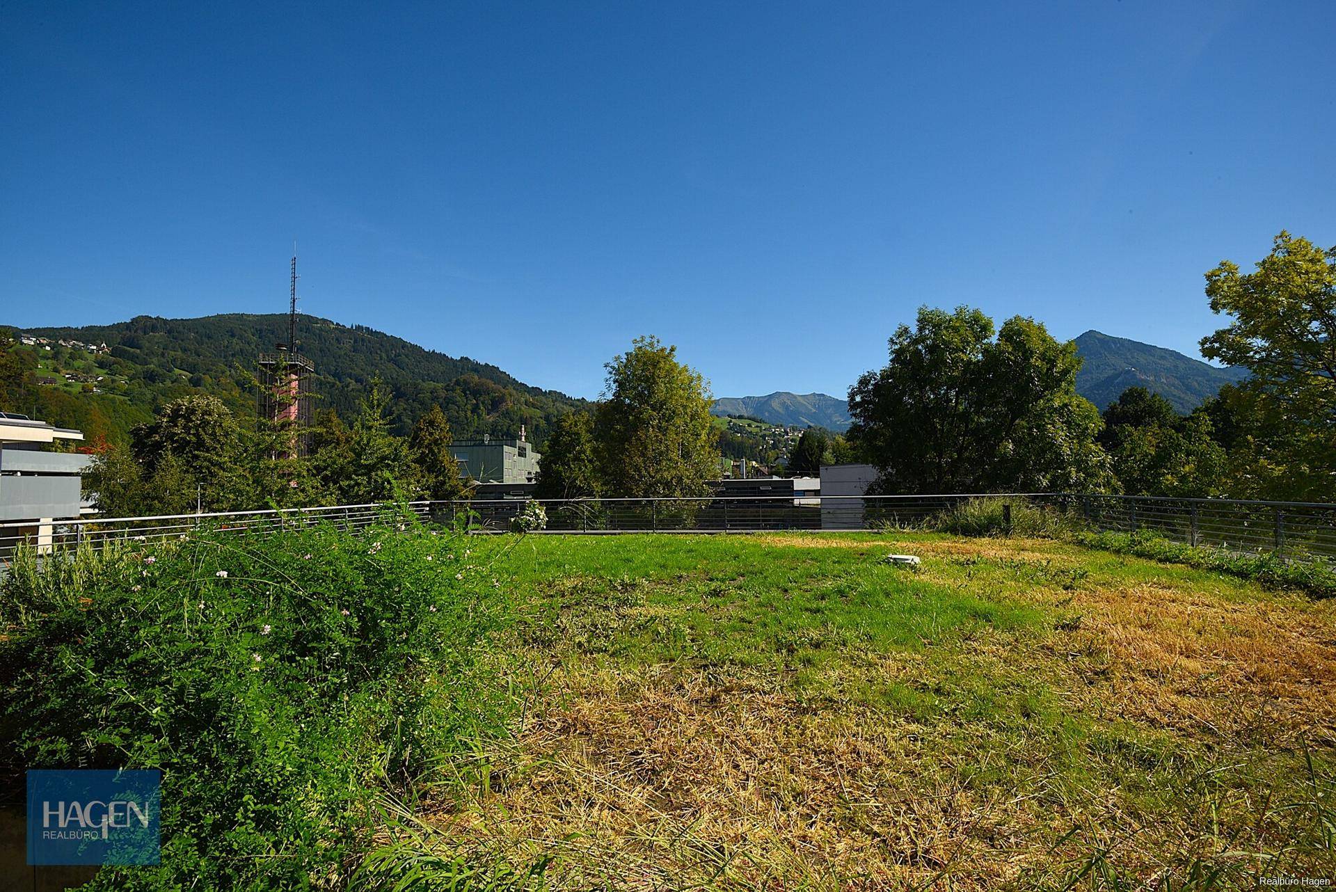 Weitläufige Dachterrasse mit Rasenfläche und Panoramablick auf die Berge.