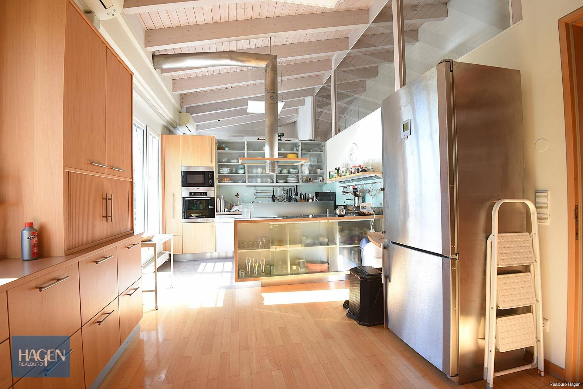 Moderne Küche mit Holzelementen, Edelstahlgeräten und offenem Design.