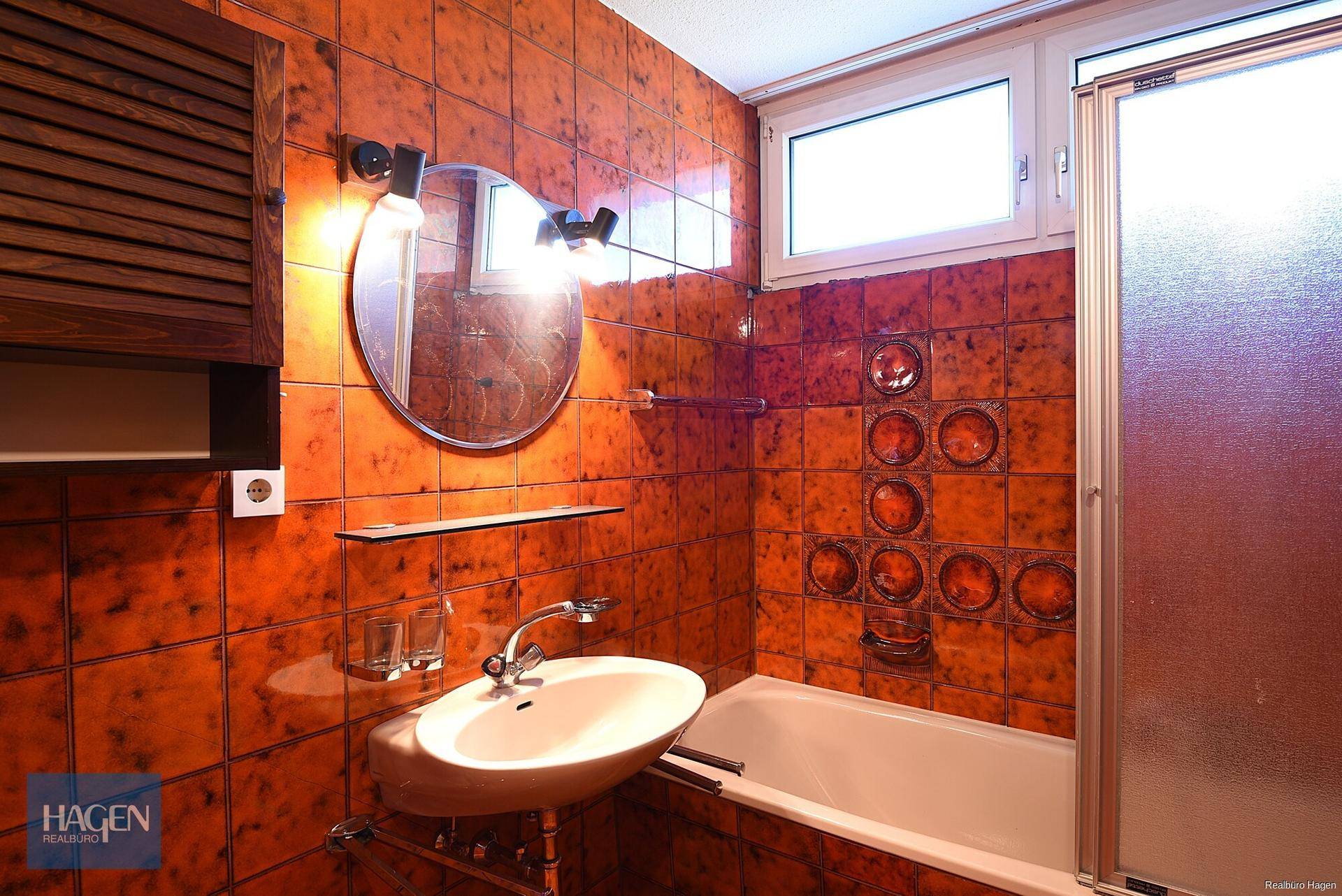 Badezimmer mit auffälligen orangefarbenen Fliesen, Badewanne, Dusche und Fenster.