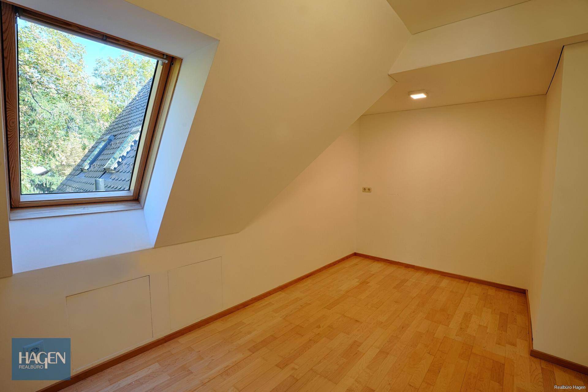 Gemütliches Zimmer im Dachgeschoss mit Holzboden und einem großen Dachfenster.