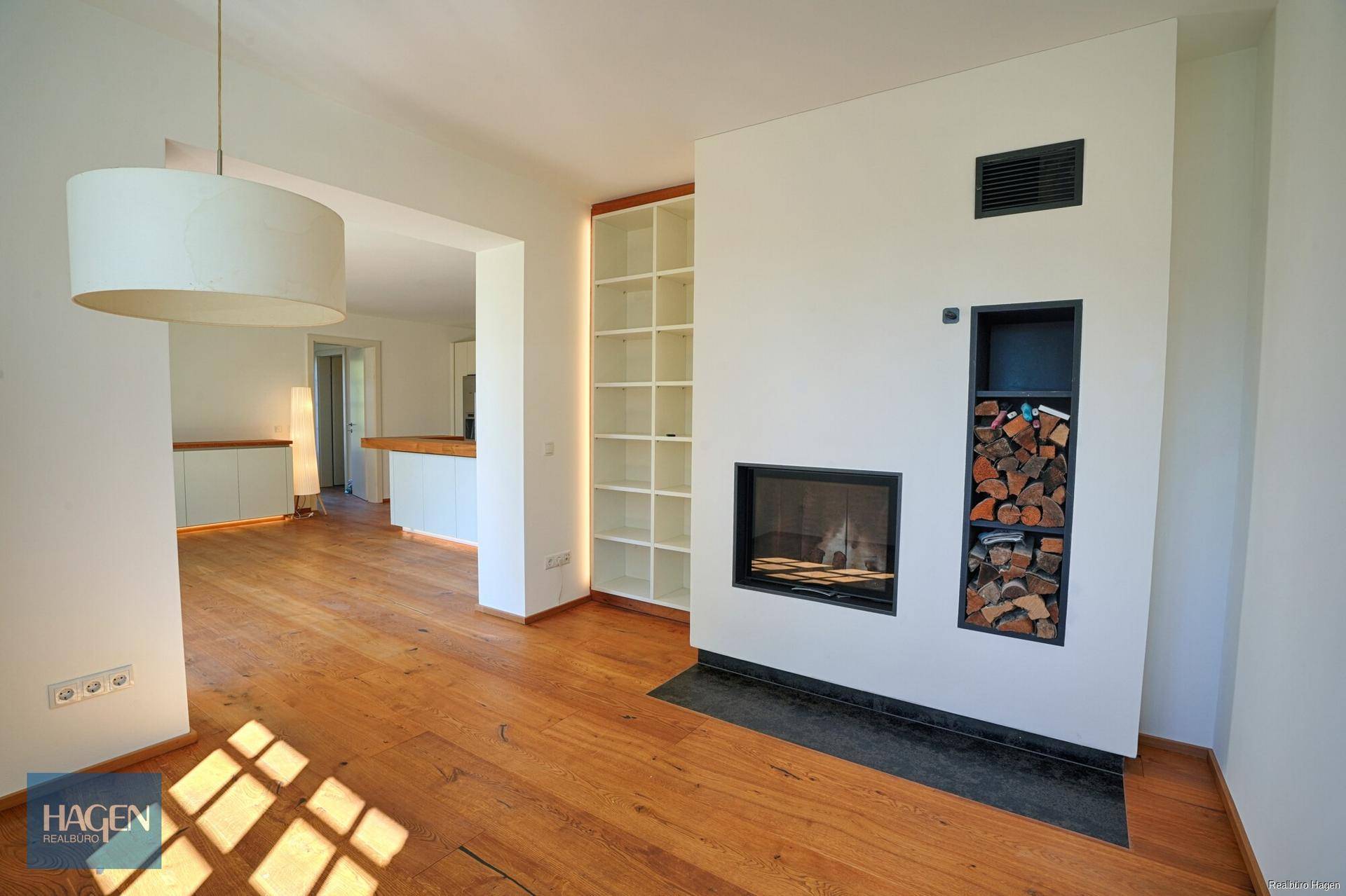 Heller Wohnbereich mit Holzboden, modernem Kamin und integrierten Bücherregalen.