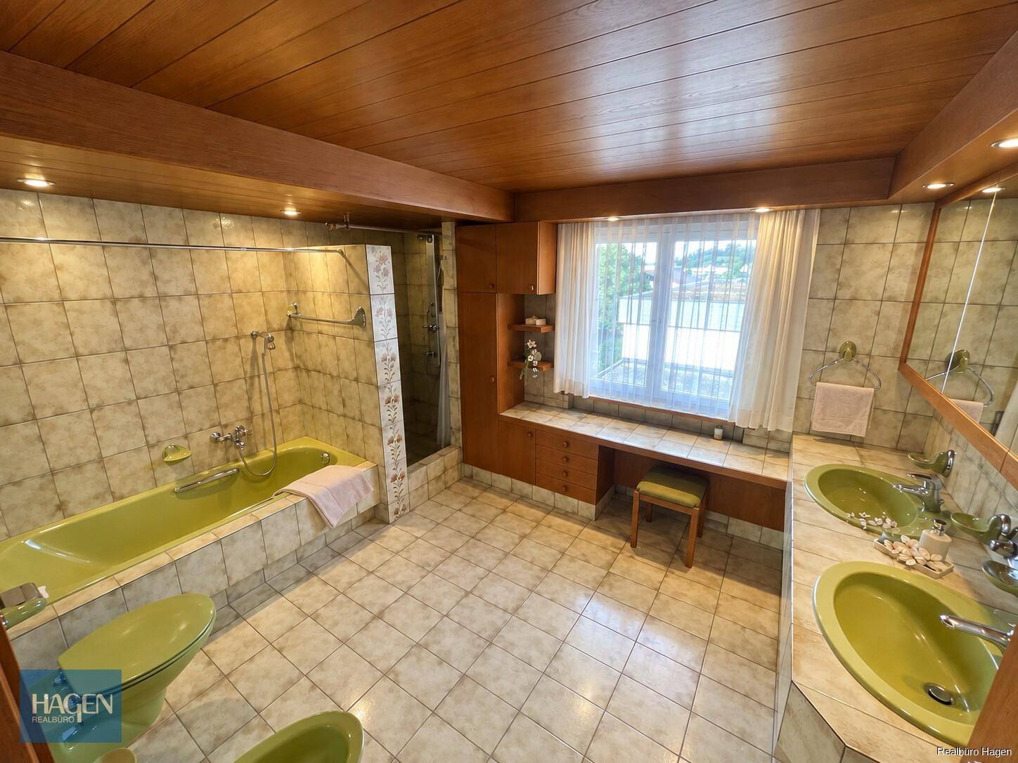 Geräumiges Badezimmer im 80er-Jahre-Stil mit grünen Armaturen, Badewanne und Dusche.