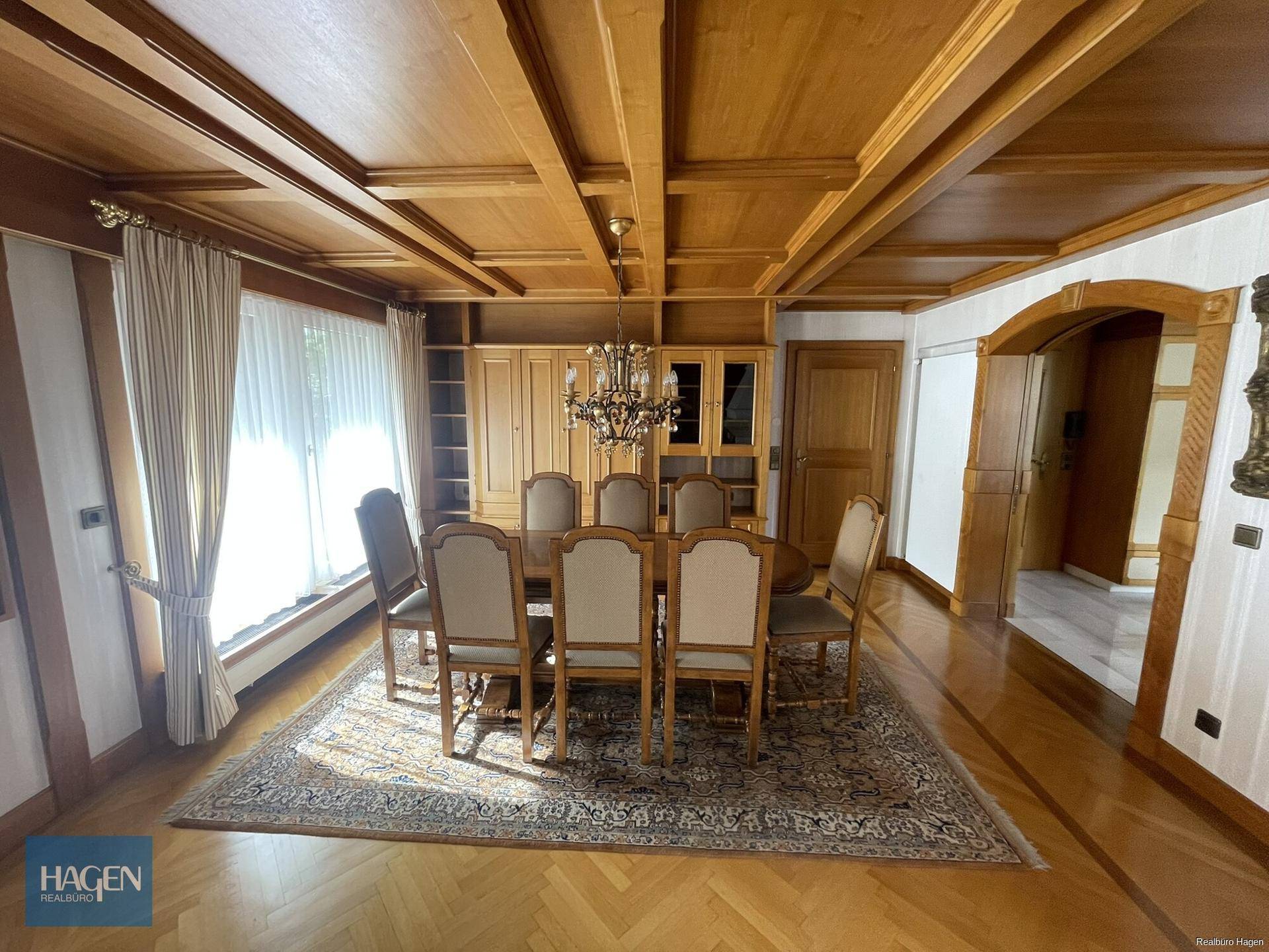 Eleganter Essbereich mit Holzbalkendecke, Parkettboden und großem Esstisch für zehn Personen.