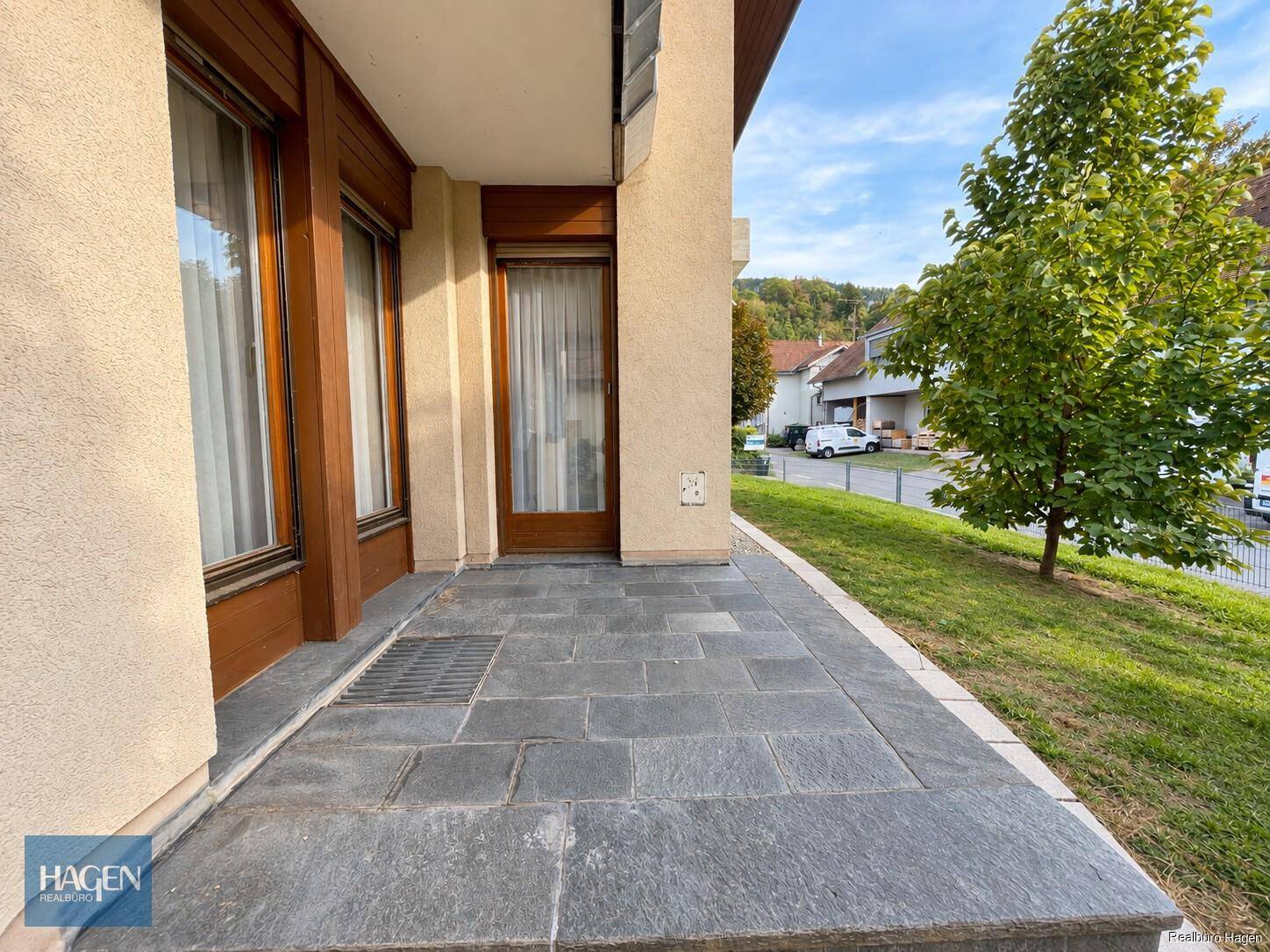 Kleine, gepflasterte Terrasse am Gebäude mit Zugang zu den Innenräumen.