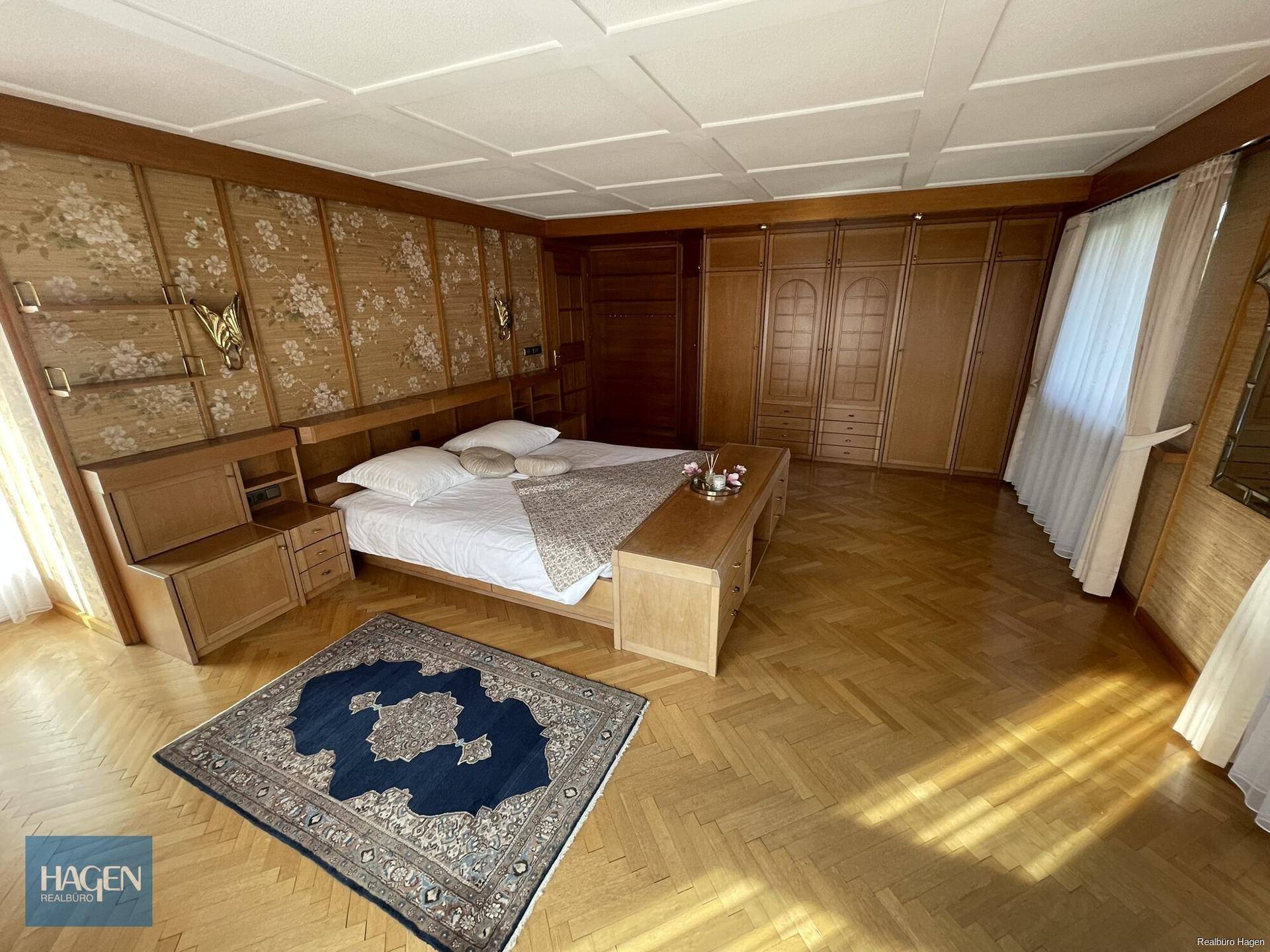 Geräumiges Schlafzimmer mit Doppelbett, Parkettboden und Einbauschränken.