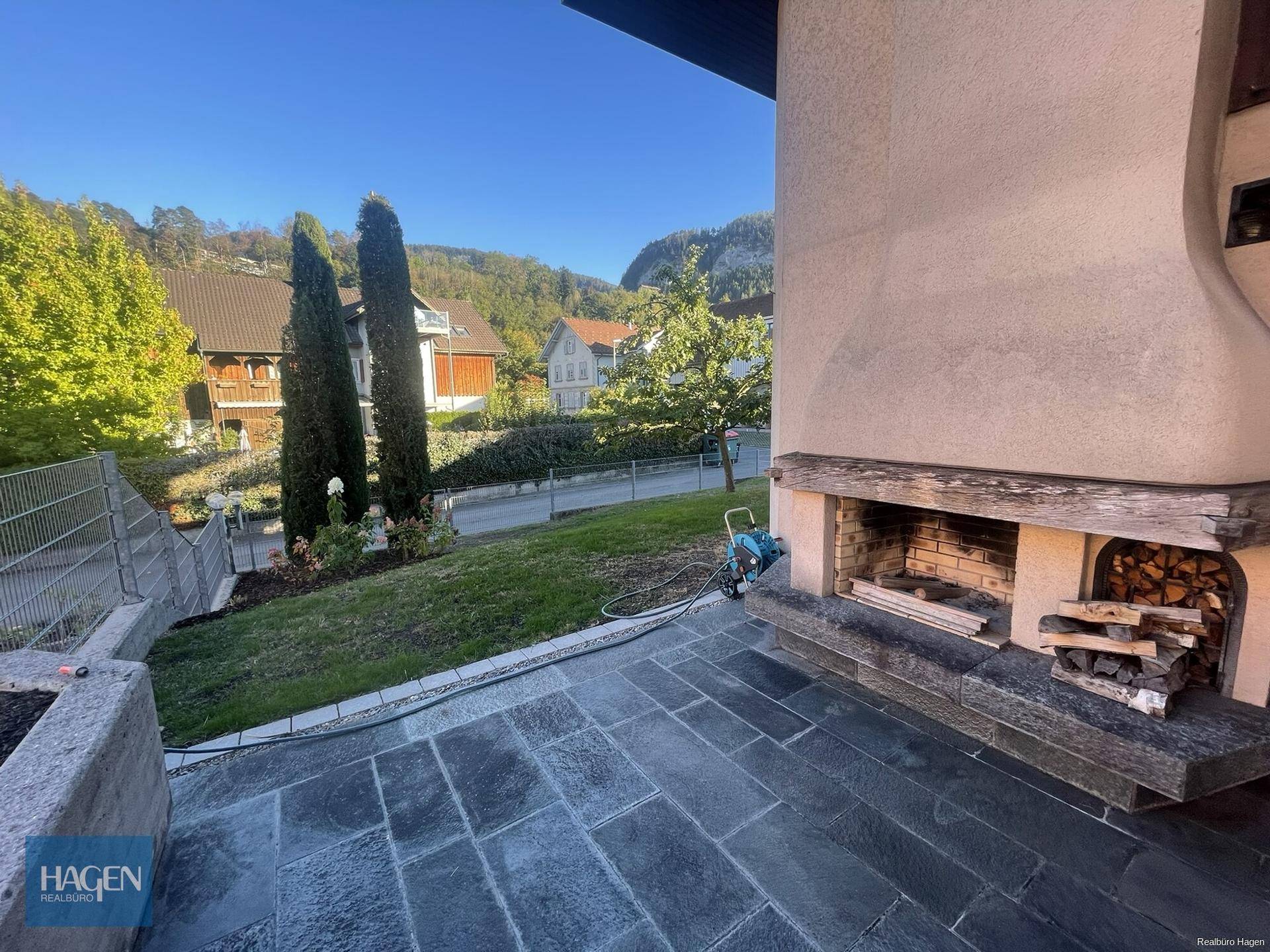 Steingepflasterte Terrasse mit Außenkamin und Blick auf die umliegende Landschaft.