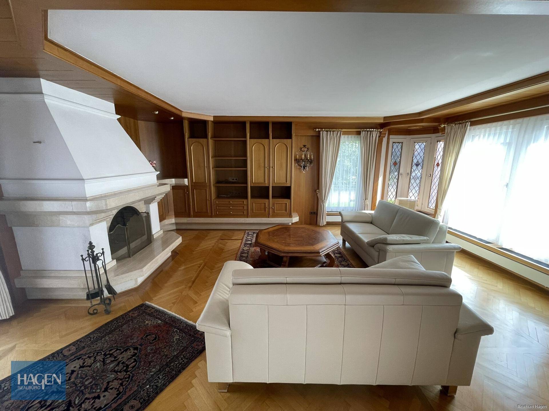 Gemütliches Wohnzimmer mit Kamin, Parkettboden und hellen Sofas.