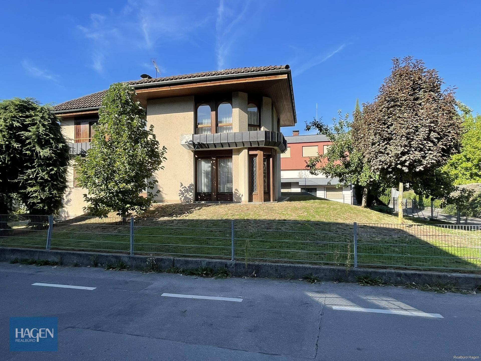 Attraktives Einfamilienhaus mit traditioneller Architektur, großen Fenstern und gepflegtem Vorgarten.