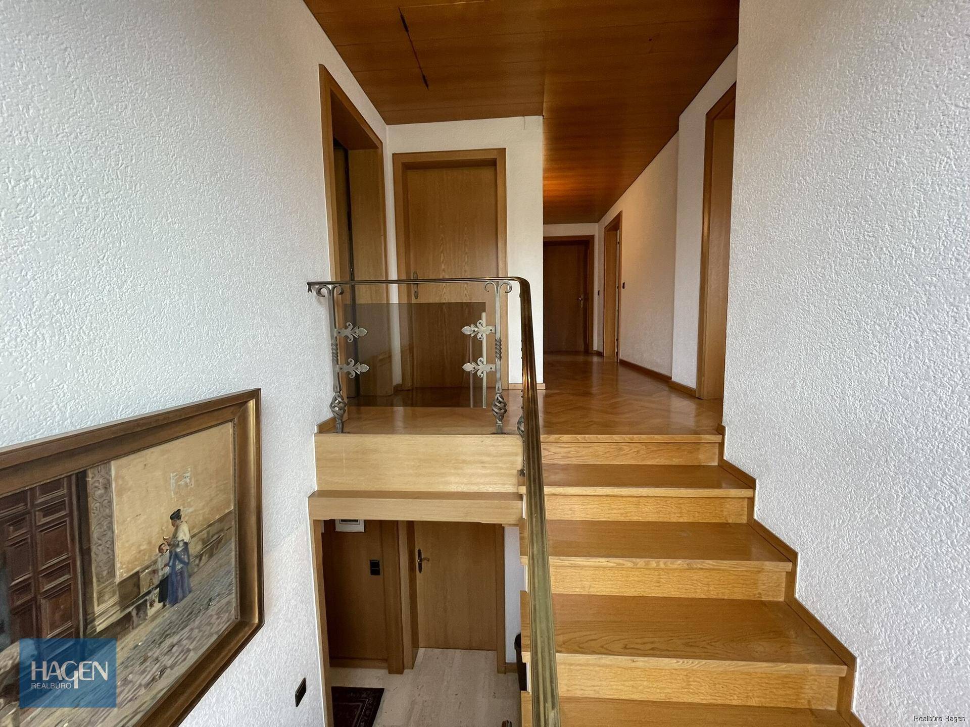 Heller Treppenaufgang mit Holzstufen und Geländer, führt zu weiteren Zimmern.