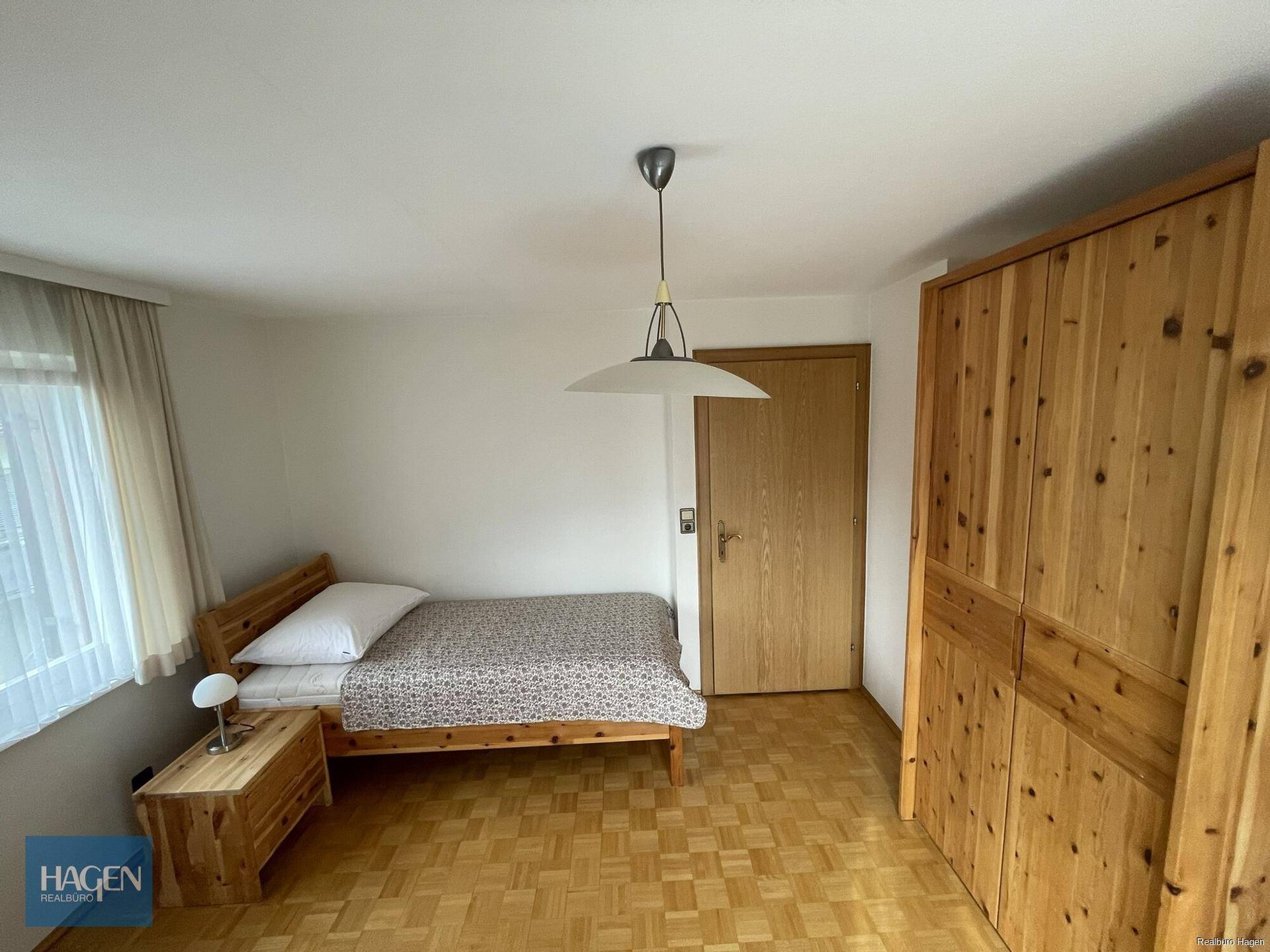 Gemütliches Schlafzimmer mit Einzelbett, Holzmöbeln und Parkettboden.