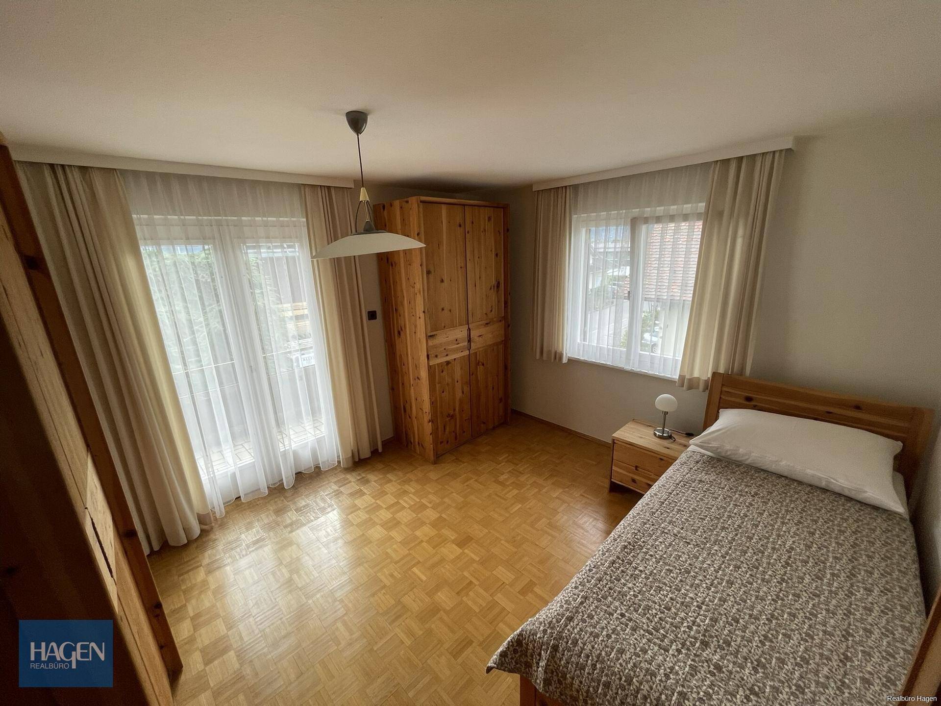 Helles Schlafzimmer mit Einzelbett, Holzschrank und Parkettboden.