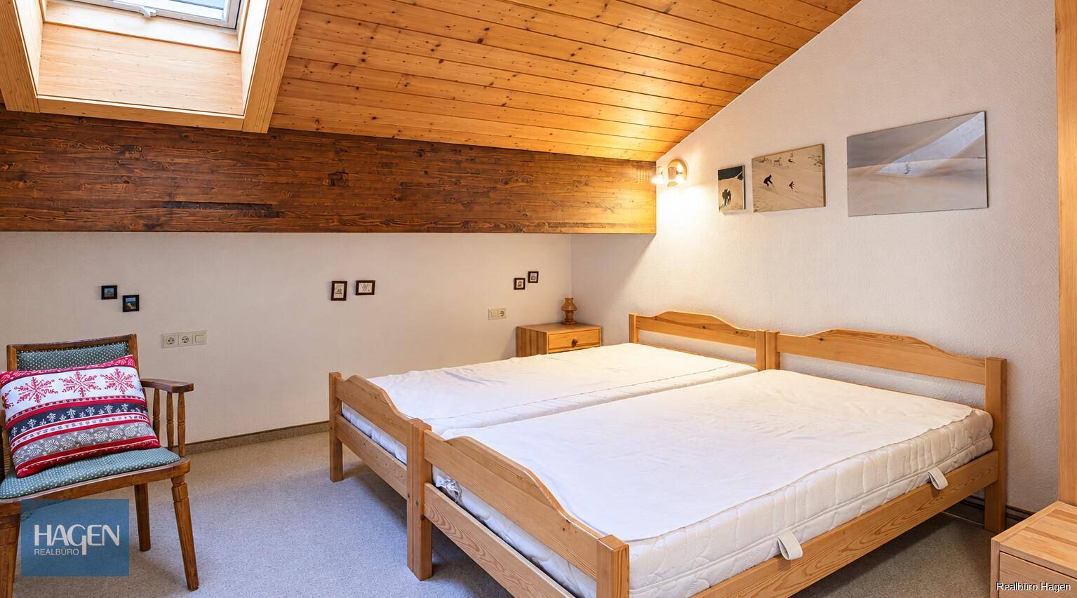 Gemütliches Schlafzimmer mit zwei Einzelbetten, Dachschräge und hellem Dachfenster.