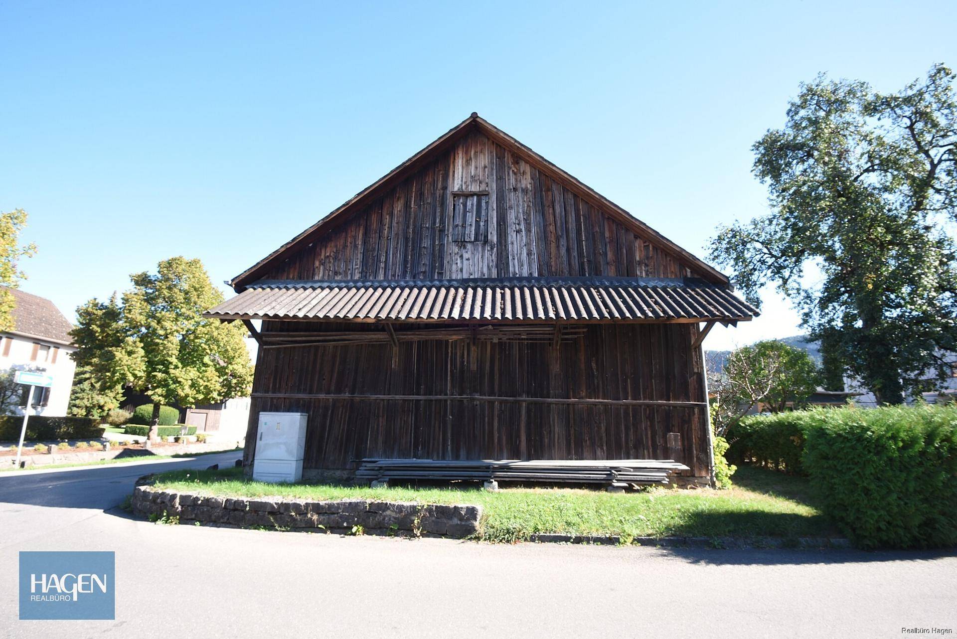 Rustikales Holzgebäude mit Giebeldach und traditioneller Holzverkleidung in ländlicher Umgebung.