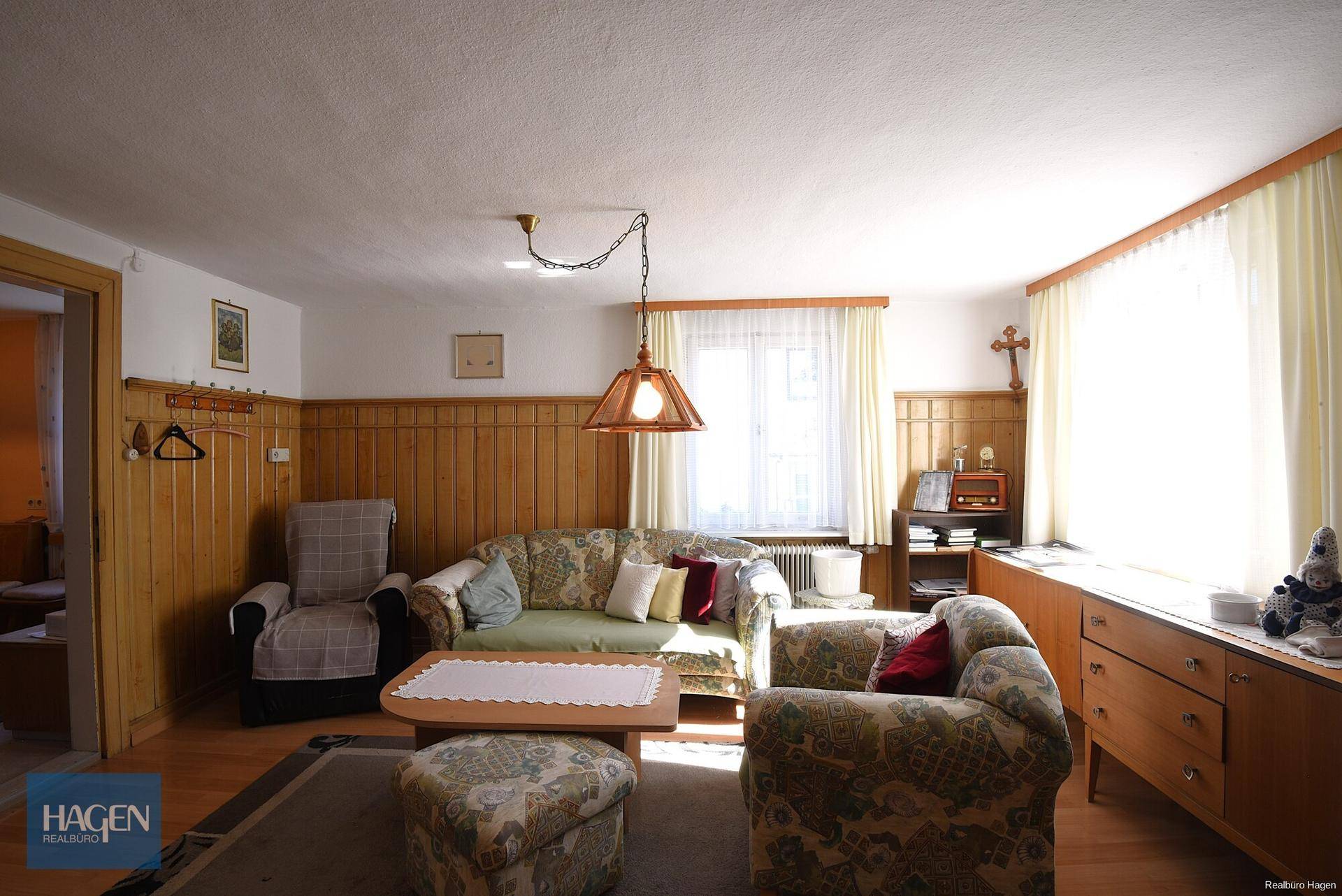 Traditionelles Wohnzimmer mit Holzvertäfelung, bequemen Sofas und viel Tageslicht.