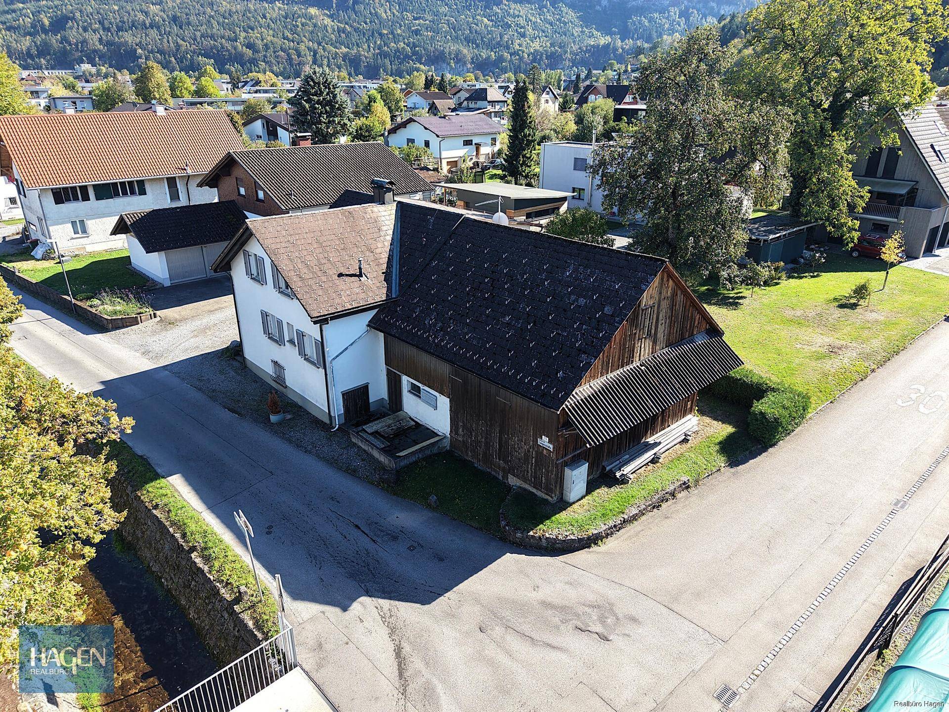 Vogelperspektive des Anwesens mit Wohnhaus, Holzschuppen und umliegenden Straßen.