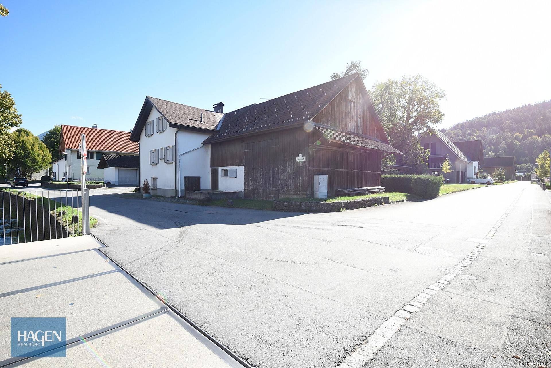 Traditionelles Wohnhaus mit angrenzendem Holzschuppen in sonniger ländlicher Lage.