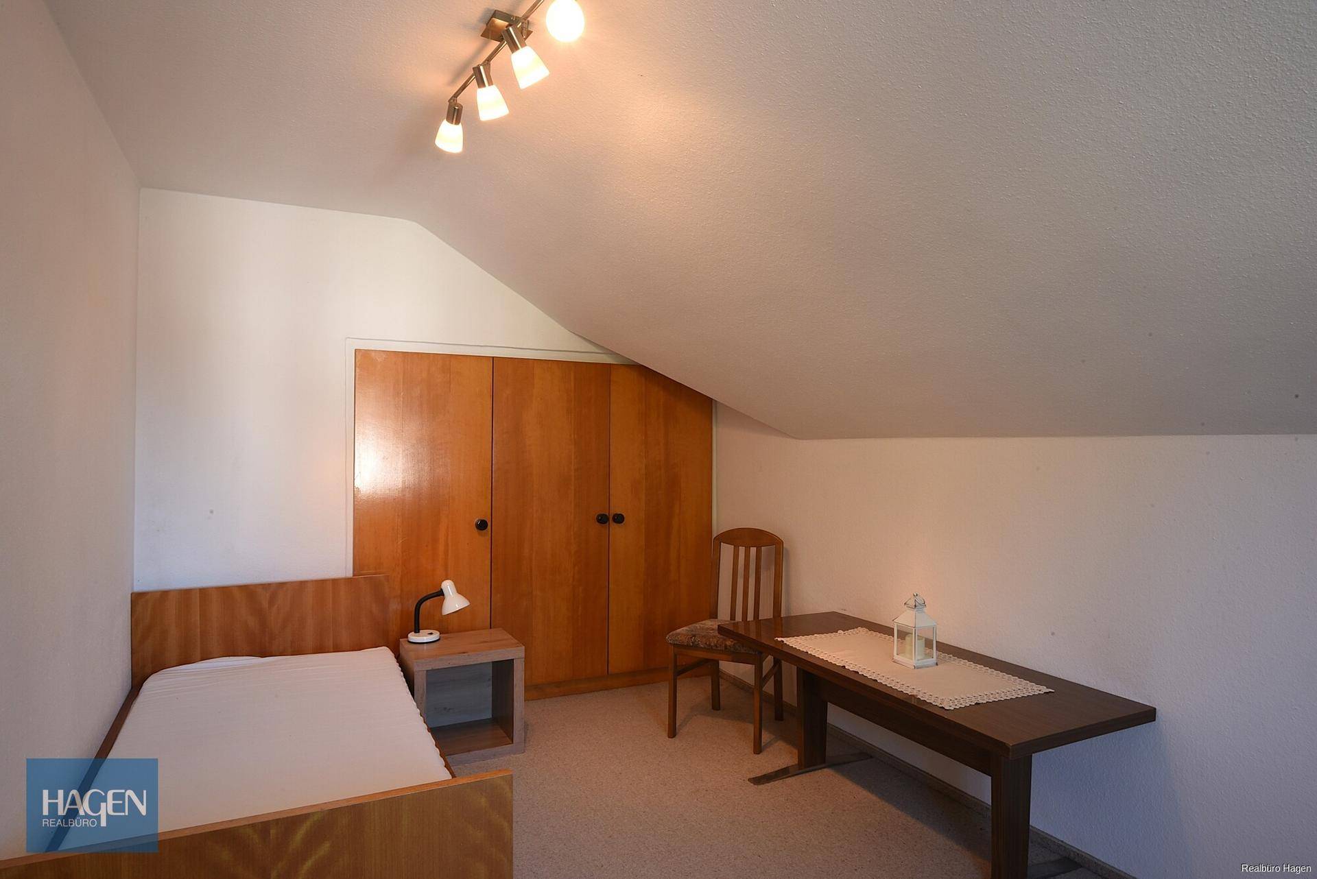 Dachschlafzimmer mit schräger Decke, Einbauschrank und Einzelbett.