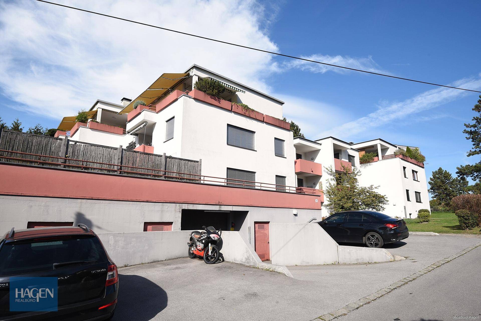 Mehrfamilienhaus mit Tiefgaragenzufahrt und Außenparkplätzen in sonniger Lage.
