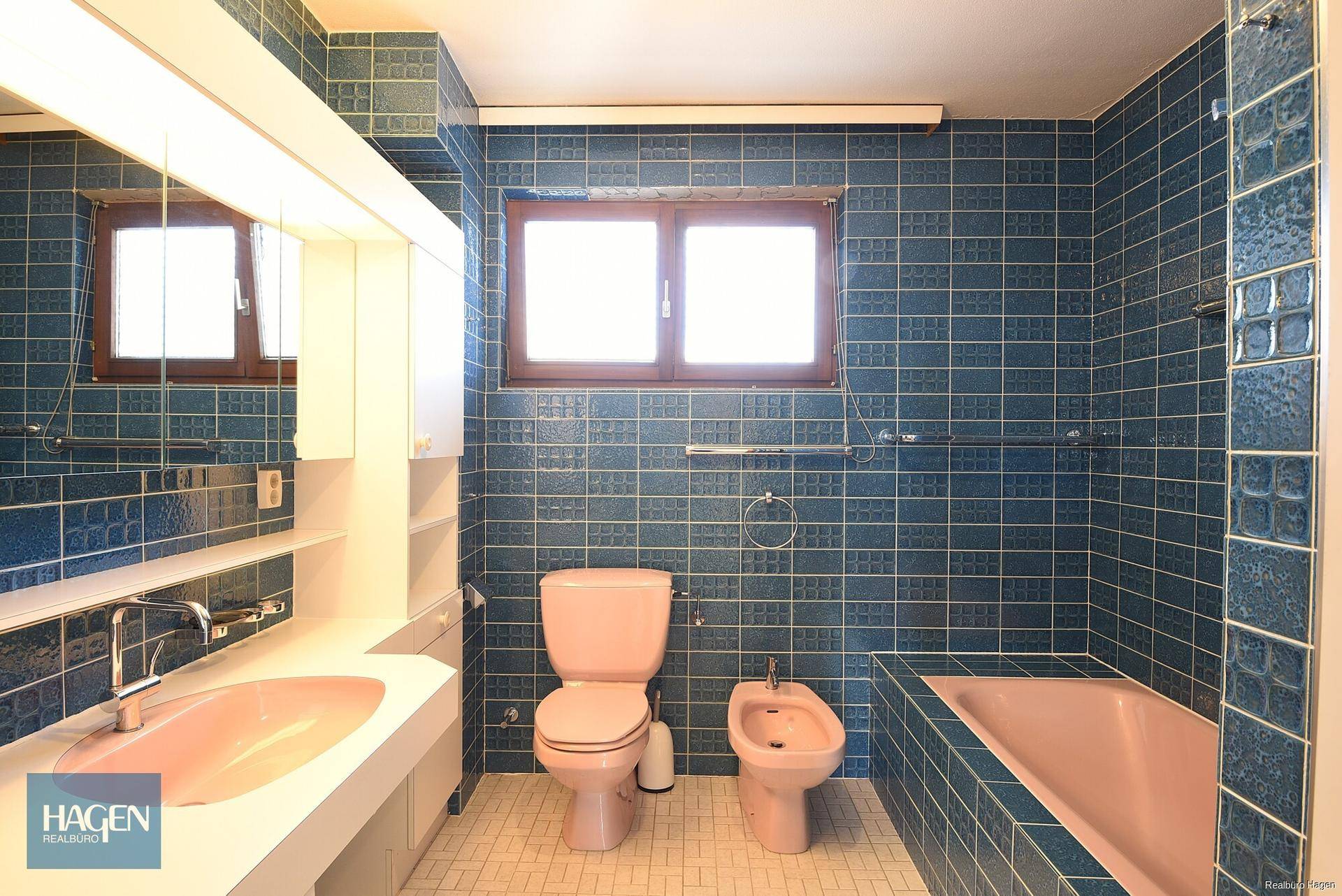 Badezimmer im 80er-Jahre-Stil mit blauen Fliesen, Badewanne, Bidet und Fenster.