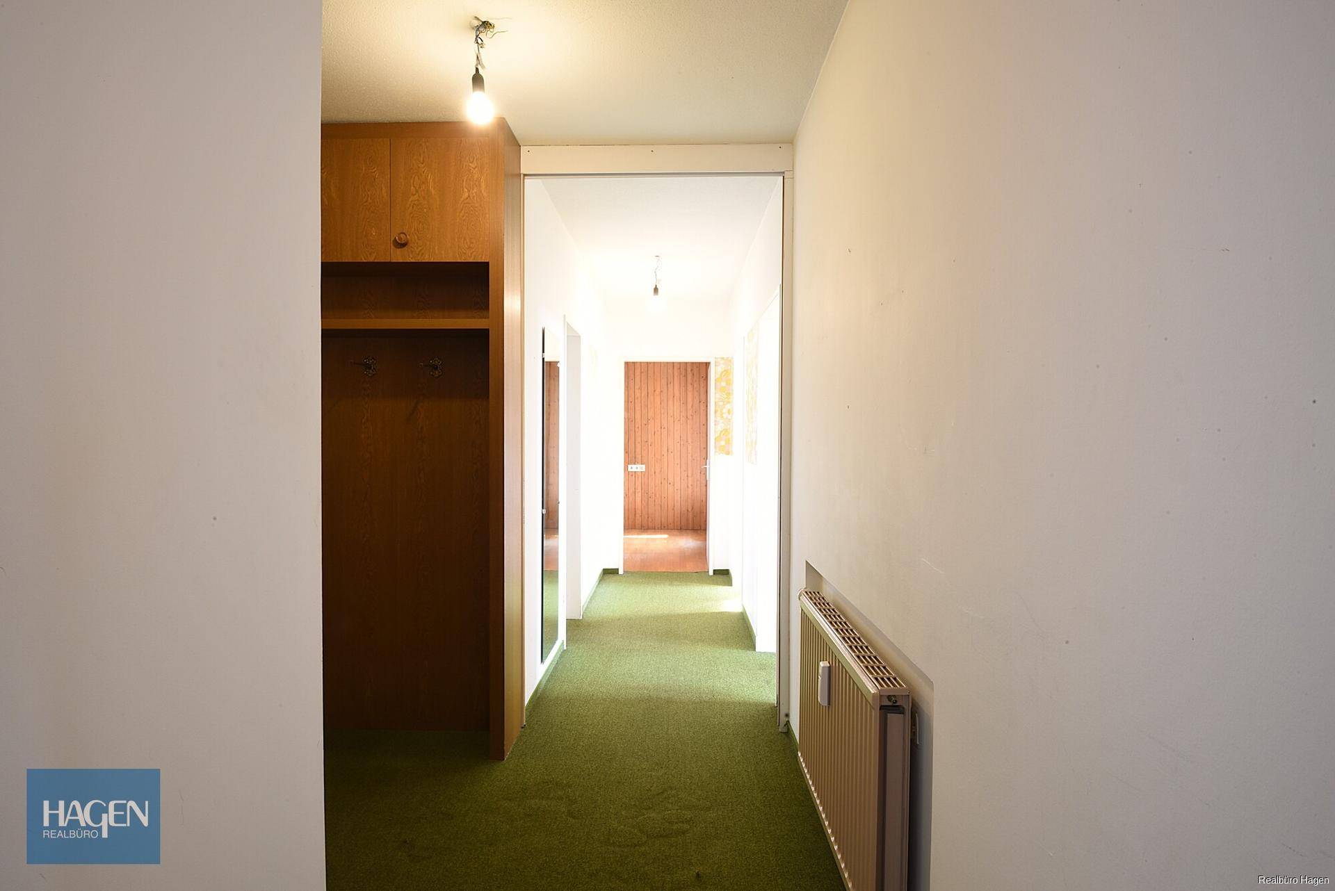 Flur mit Teppichboden und integrierter Garderobe, führt zu weiteren Räumen.