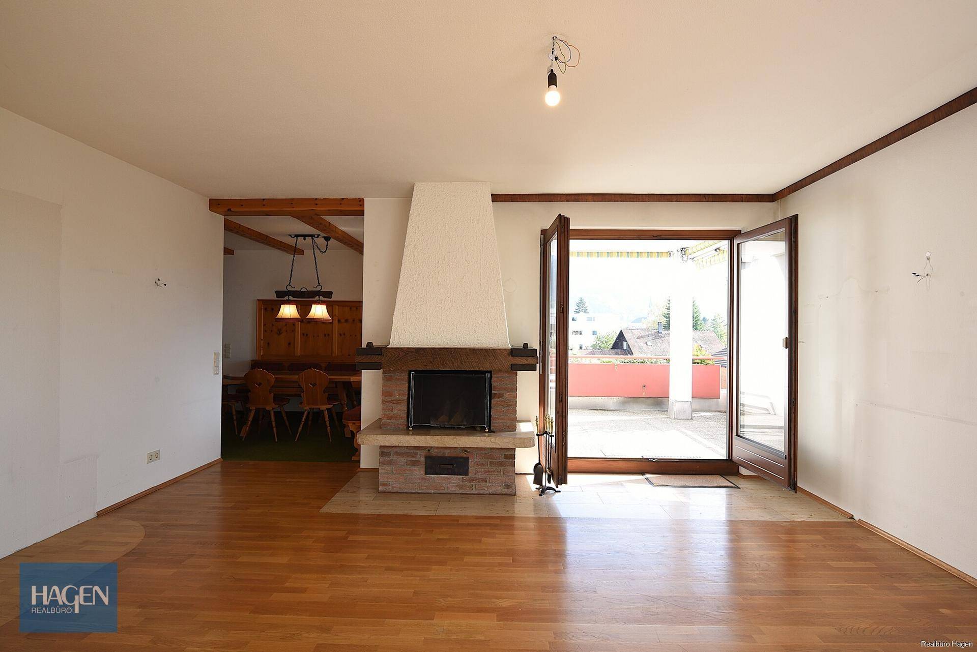 Geräumiges Wohnzimmer mit Kamin, Parkettboden und Zugang zu einer großen Terrasse.