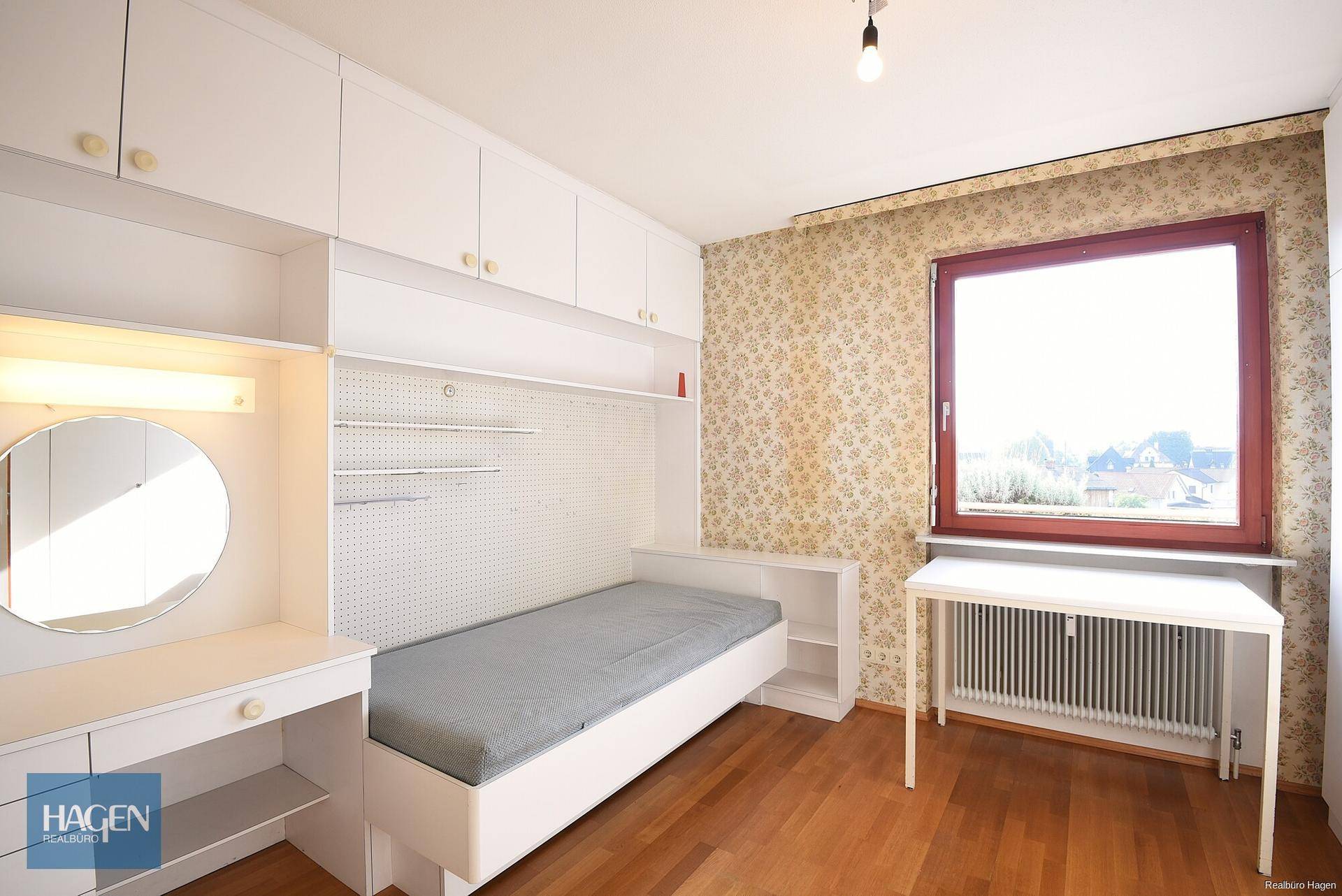 Kinderzimmer mit Einbauschrank, Schreibtisch und Parkettboden, hell und funktional.