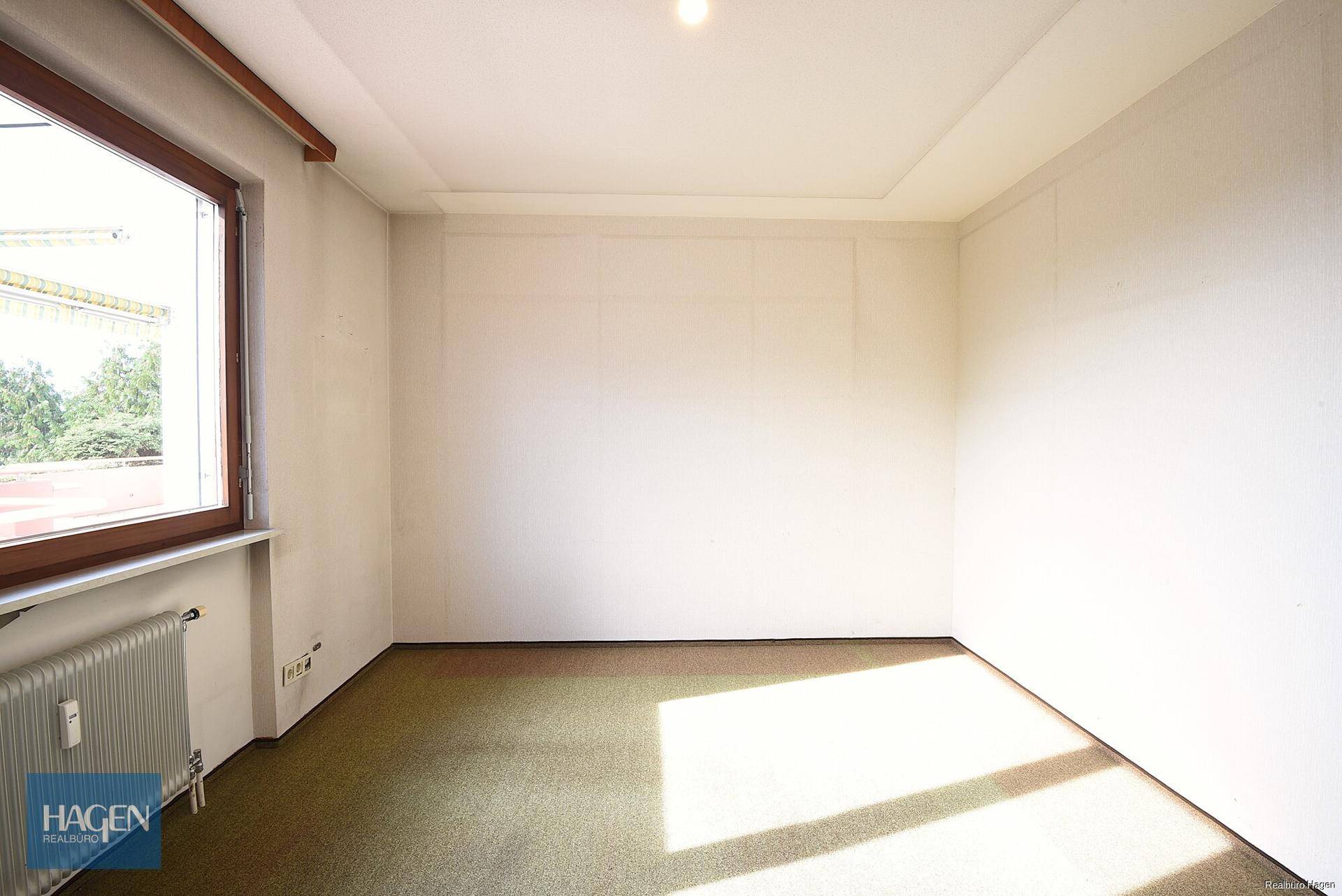 Helles Zimmer mit Teppichboden und großem Fenster, vielseitig nutzbar.