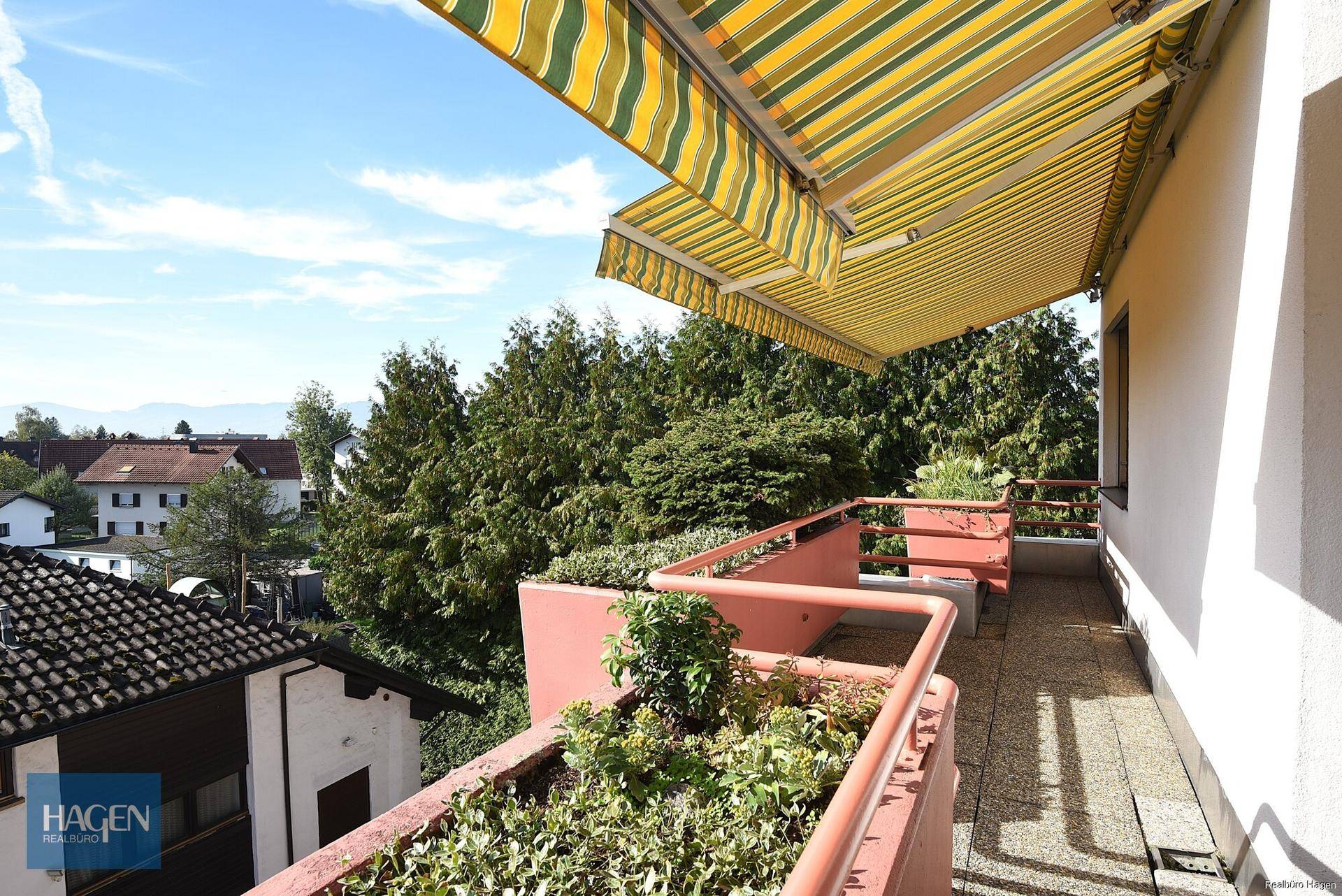 Langer Balkon mit Pflanzenkübeln und weitem Blick über die Baumwipfel.