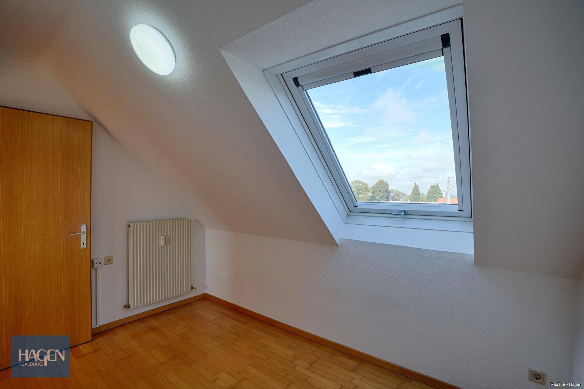 Gemütliches Dachzimmer mit Dachfenster, Parkettboden und viel Tageslicht.