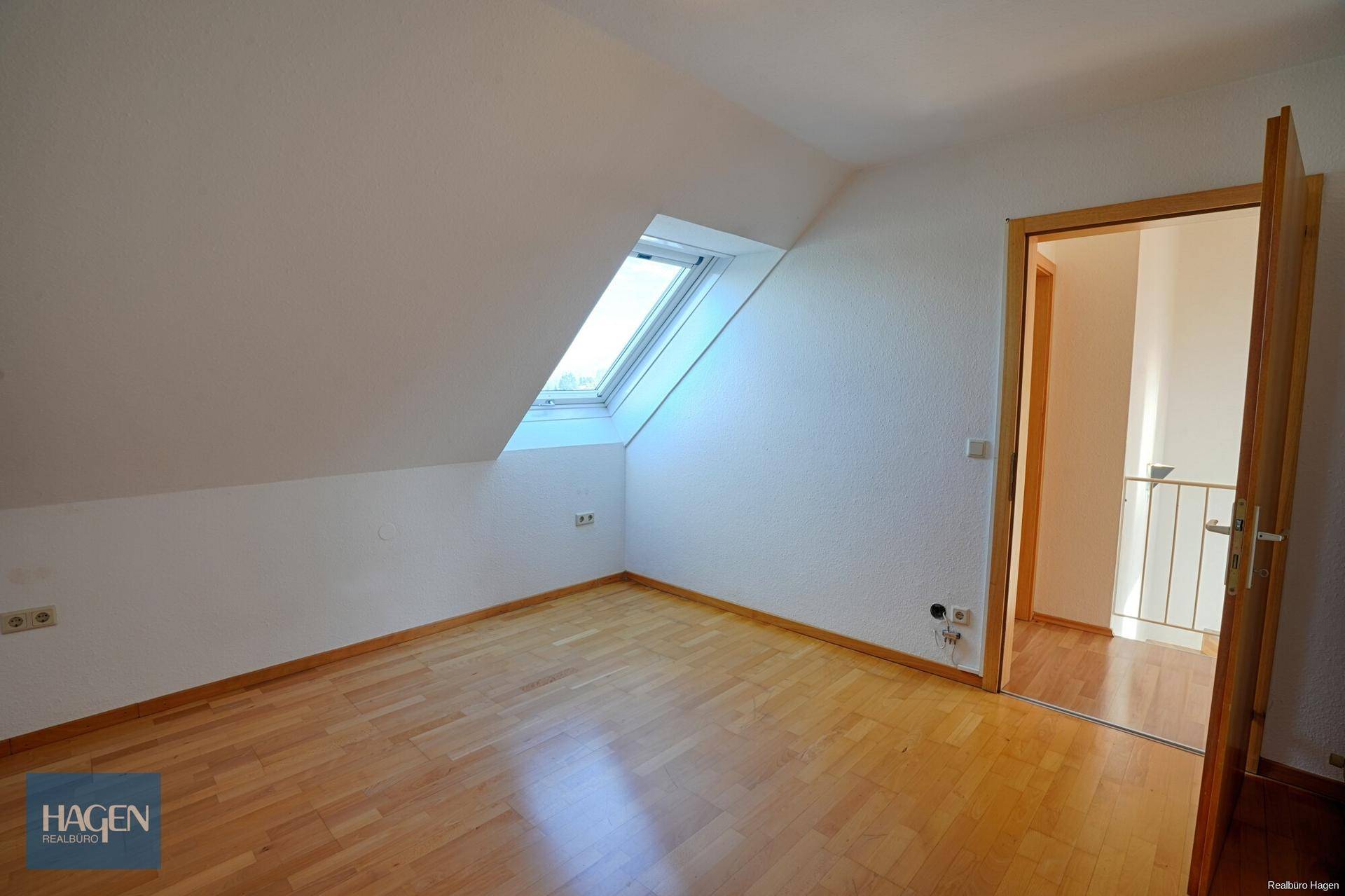 Helles Dachzimmer mit Parkettboden und schrägen Wänden, ideal als Schlaf- oder Arbeitszimmer.