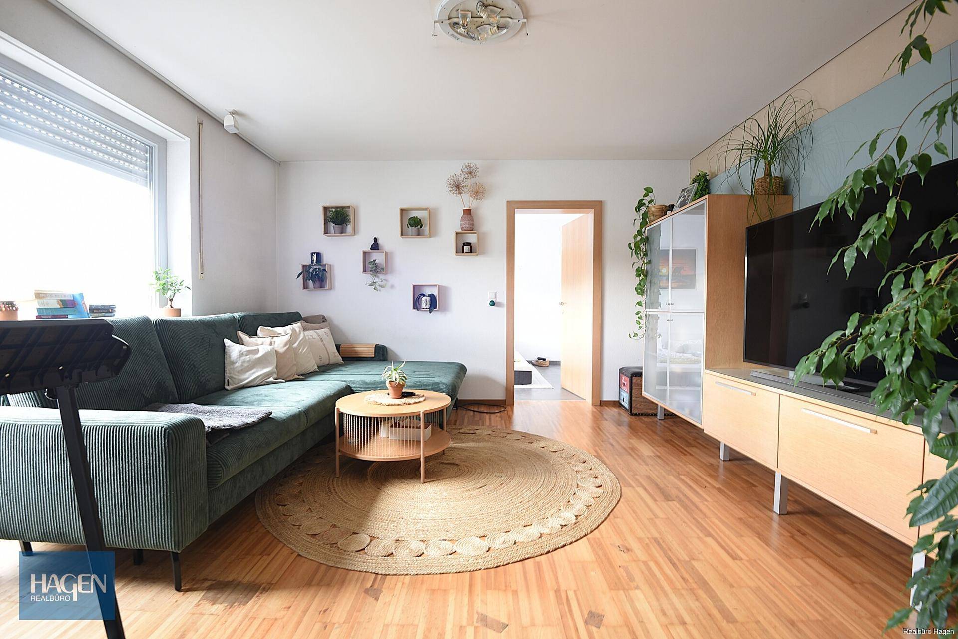 Gemütliches Wohnzimmer mit grünem Sofa, Holzboden und modernen Dekorationselementen.