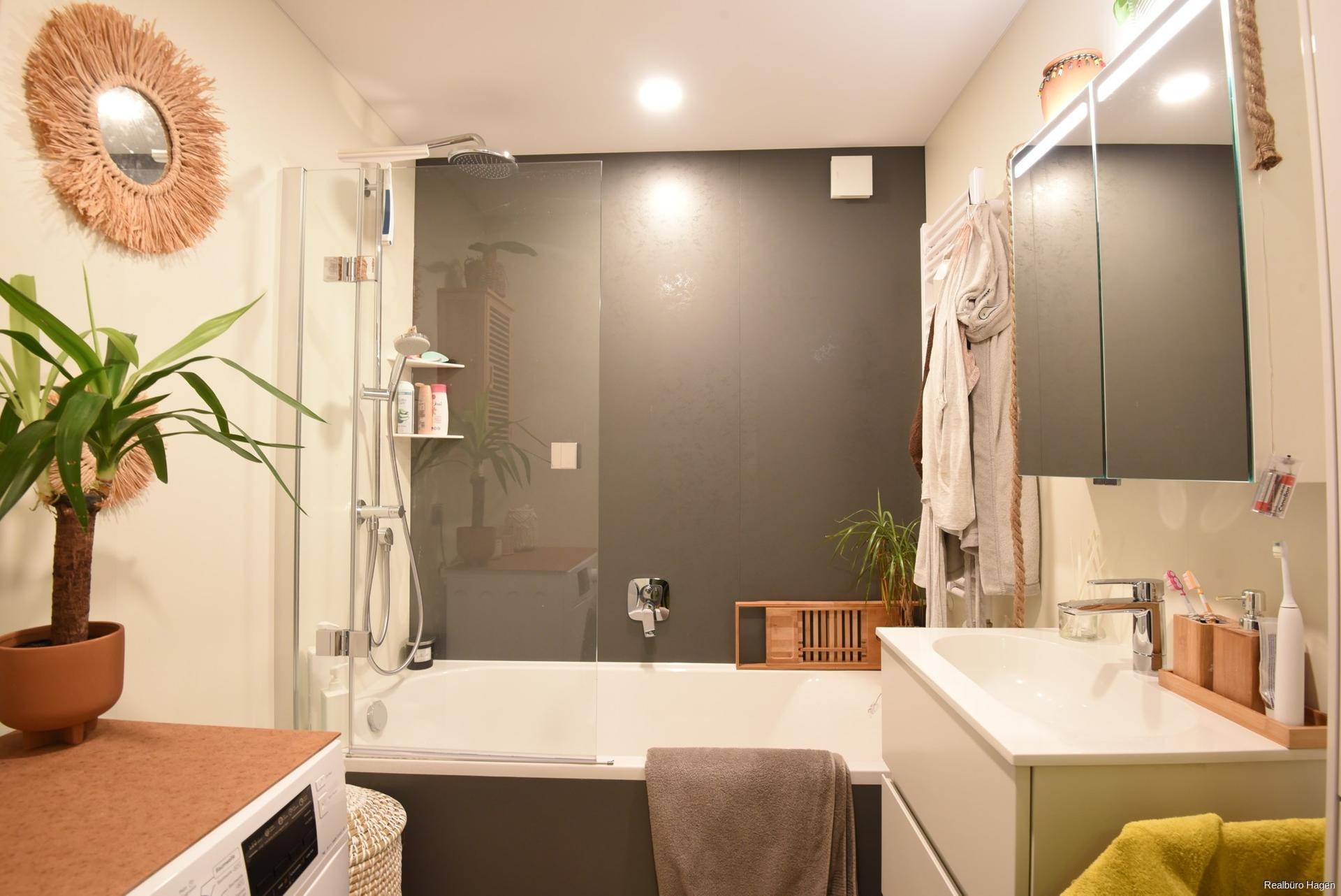 Modernes Badezimmer mit Badewanne, Duschbereich und Waschbecken mit Spiegelschrank.