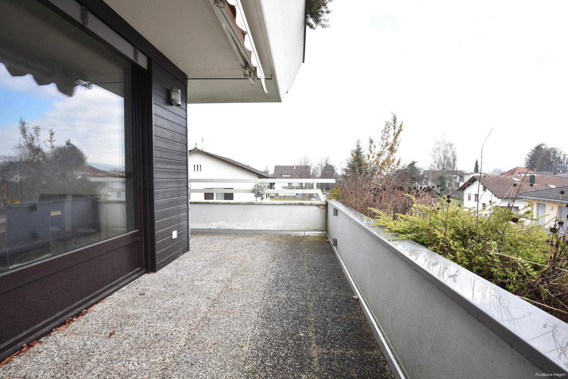 Balkon mit Betonboden und Blick auf die umliegenden Häuser und Bäume.