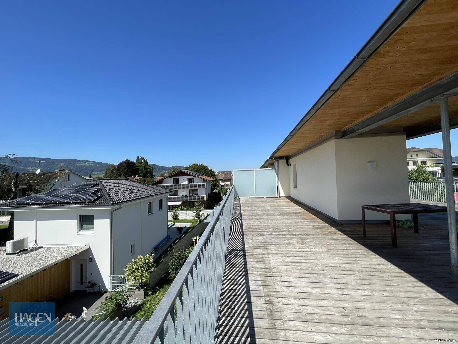 Sonniger Tag auf der Holzterrasse mit Blick auf die umliegende Landschaft und Berge.