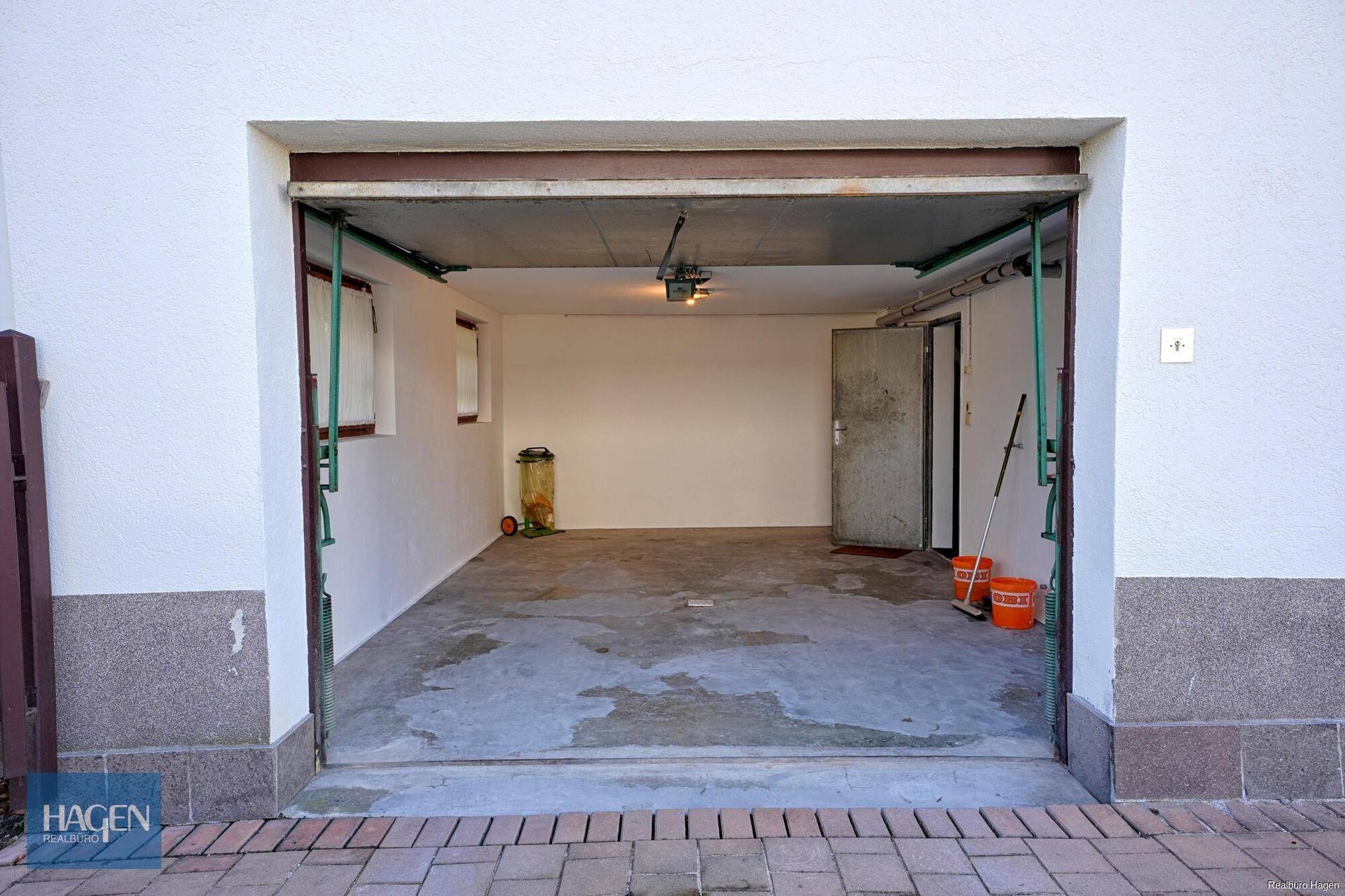 Offene Garage mit Betonboden und direktem Zugang zum Haus.