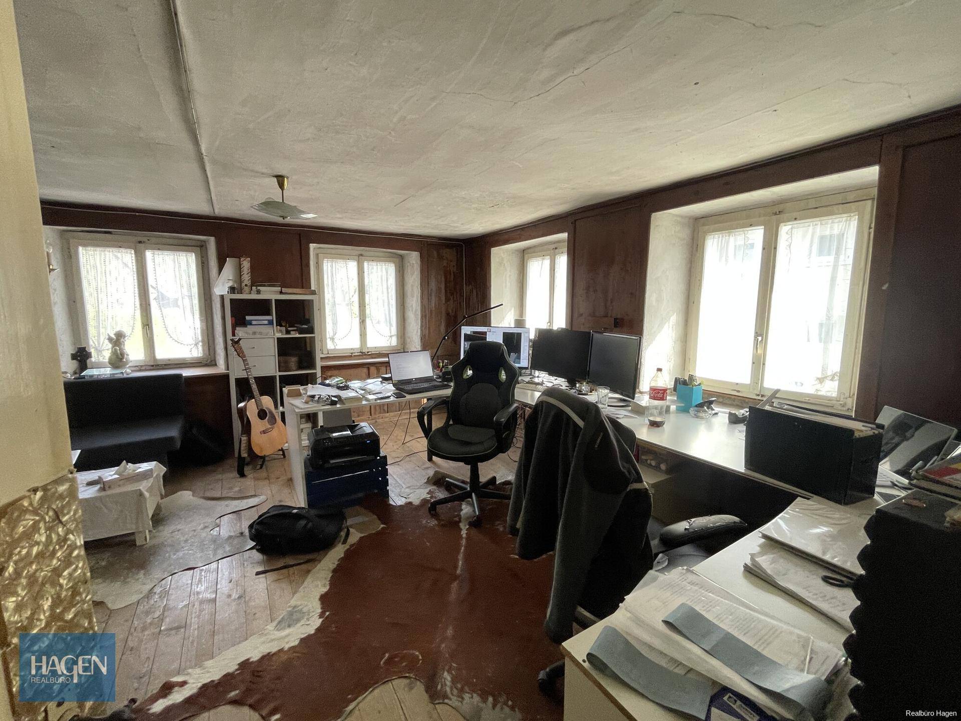 Geräumiges Arbeitszimmer mit mehreren Bildschirmen, Holzvertäfelung und viel Tageslicht.