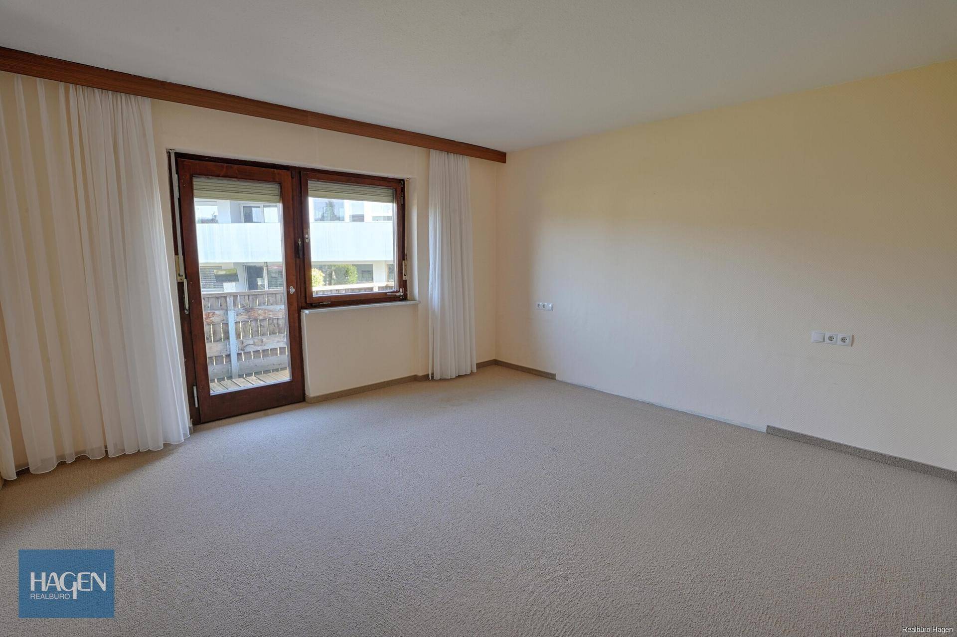Geräumiges Schlafzimmer mit Teppichboden und Zugang zu einem Balkon.