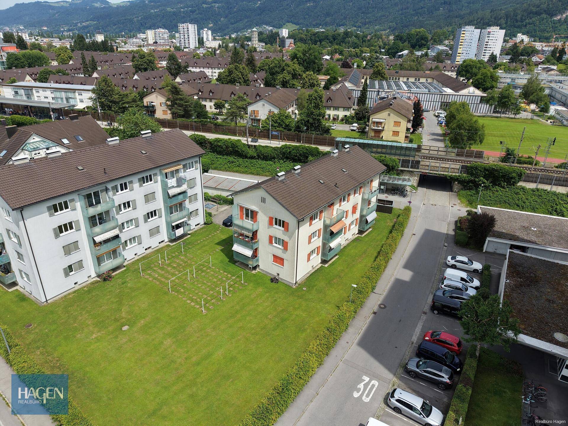 Luftaufnahme der Wohnanlage mit umliegenden Gebäuden, Grünflächen und einer weiten Aussicht.