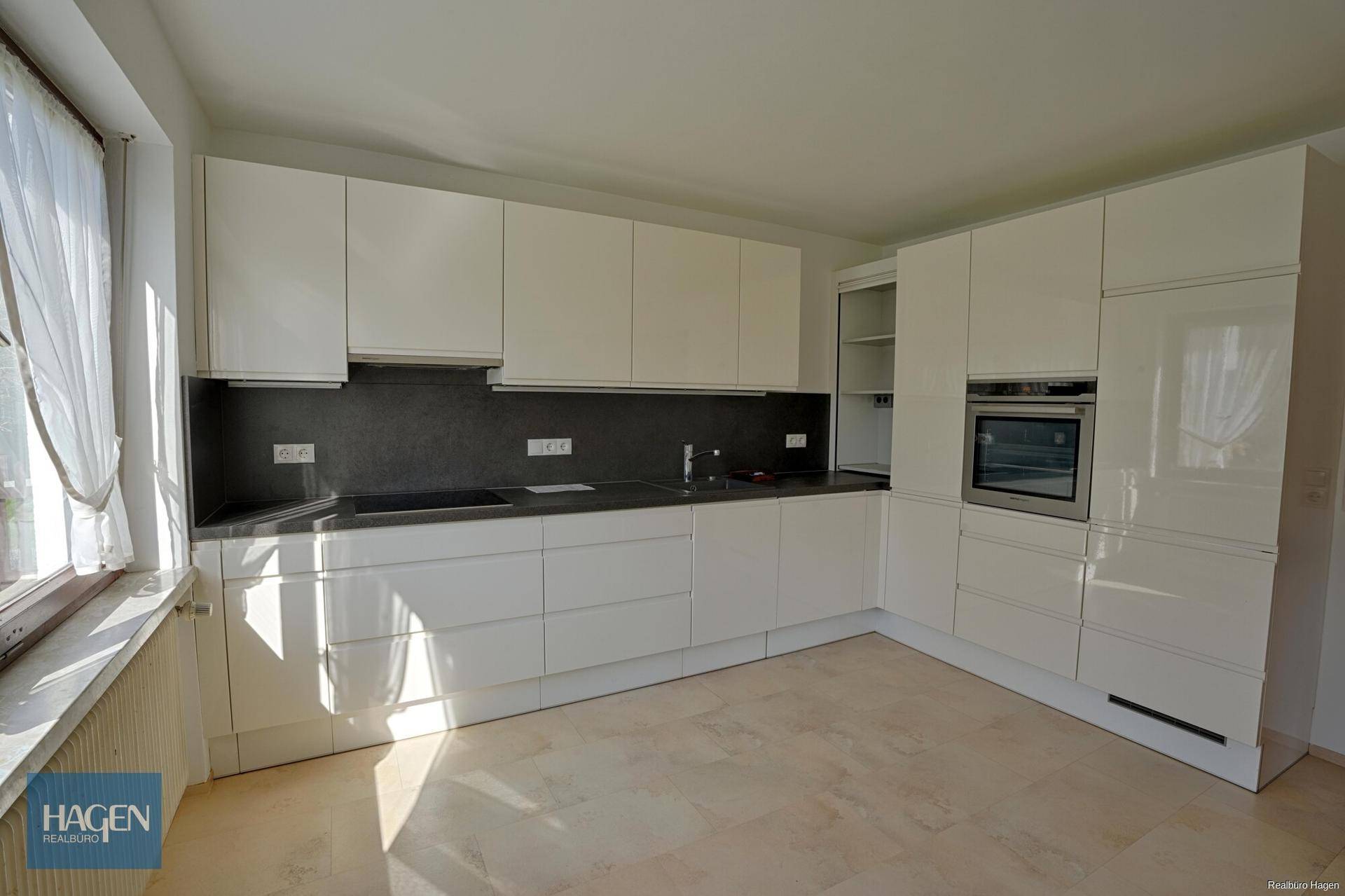 Moderne Einbauküche mit weißen Hochglanzfronten und integrierten Geräten.