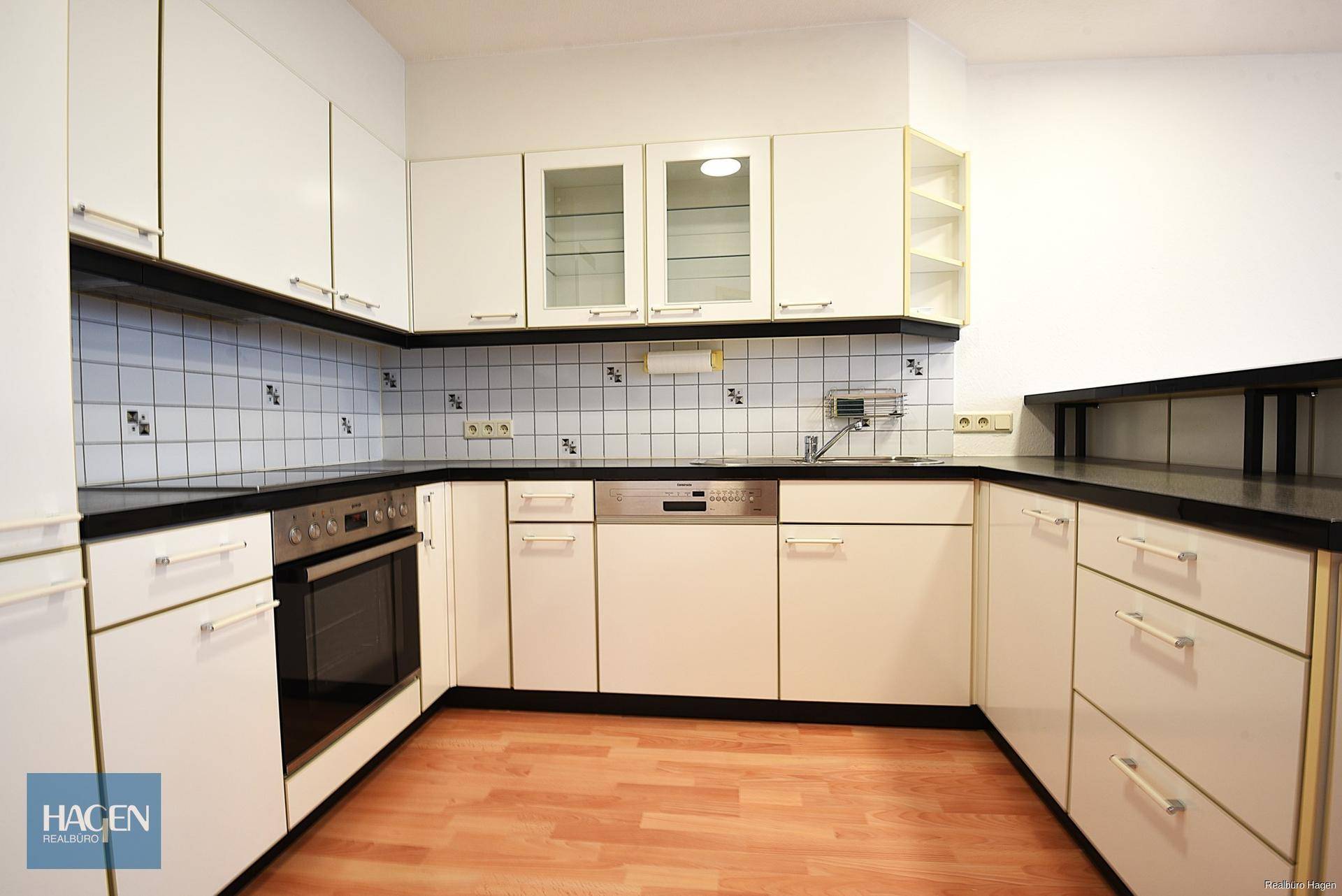 Funktionale Küche mit weißen Fronten, Fliesenrückwand und integrierten Geräten.