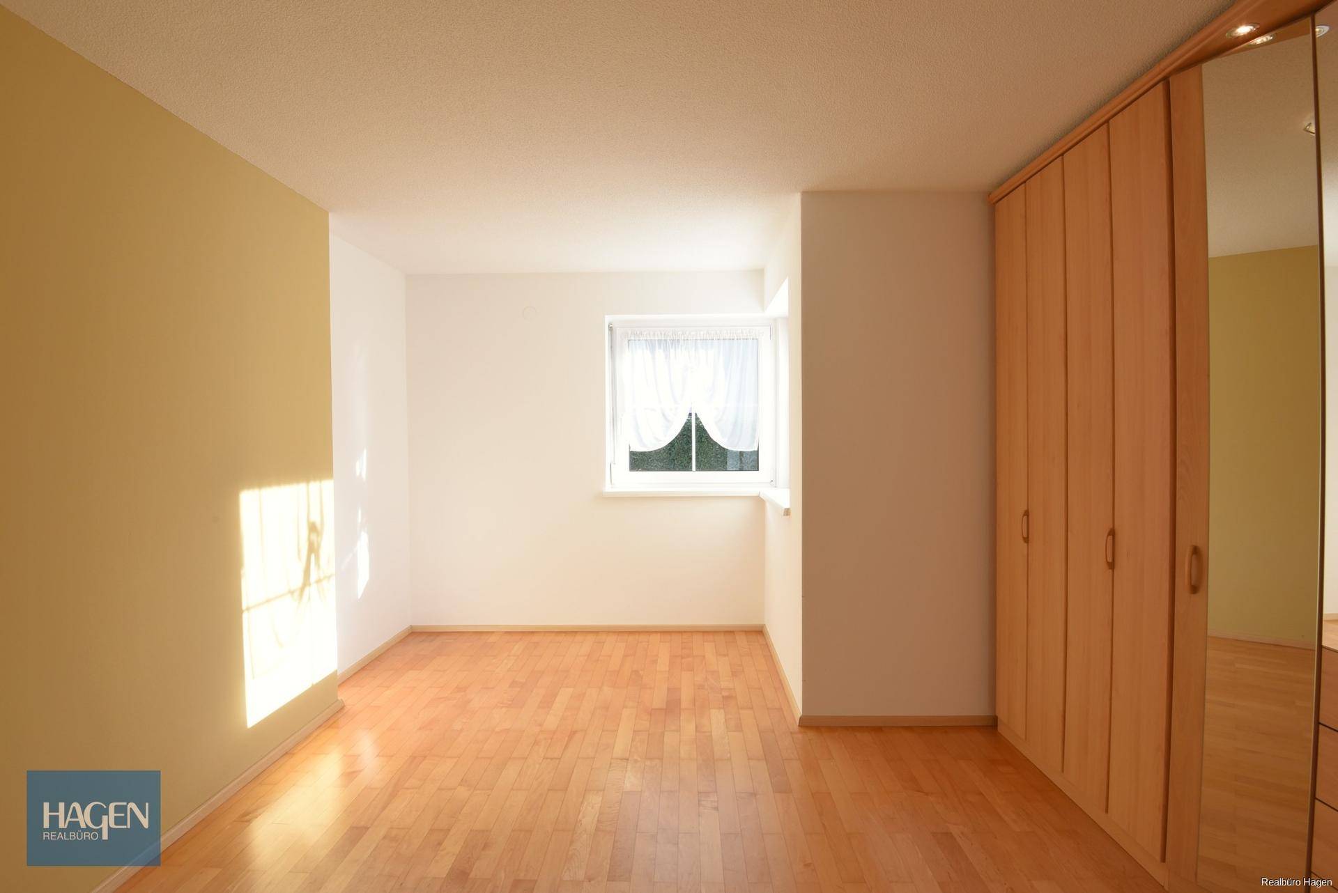 Helles Schlafzimmer mit Holzfußboden und großem Einbauschrank mit Spiegeltüren.