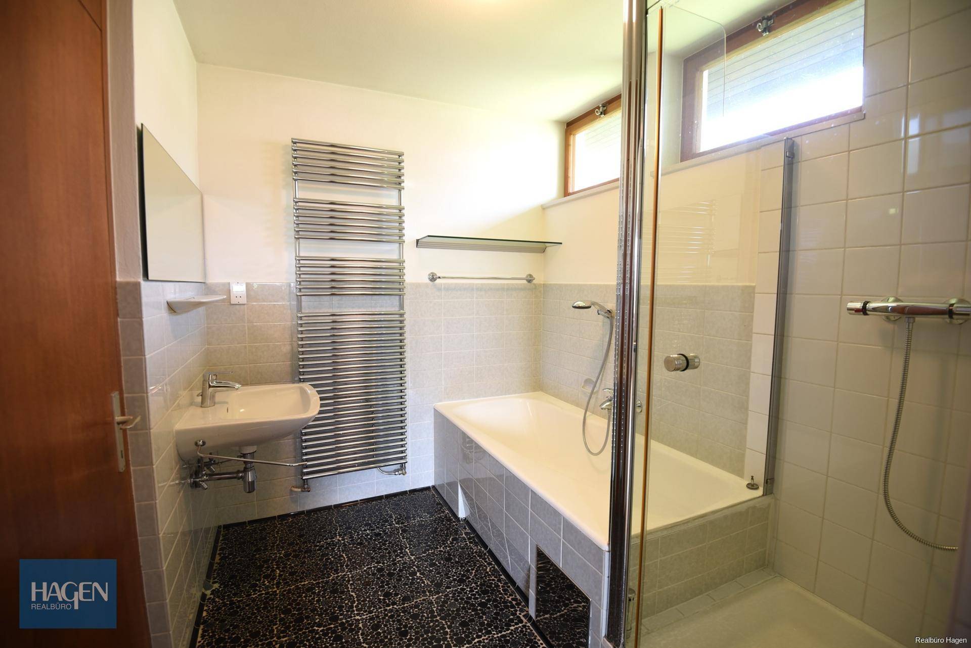 Badezimmer mit Badewanne, Dusche und beheiztem Handtuchhalter.