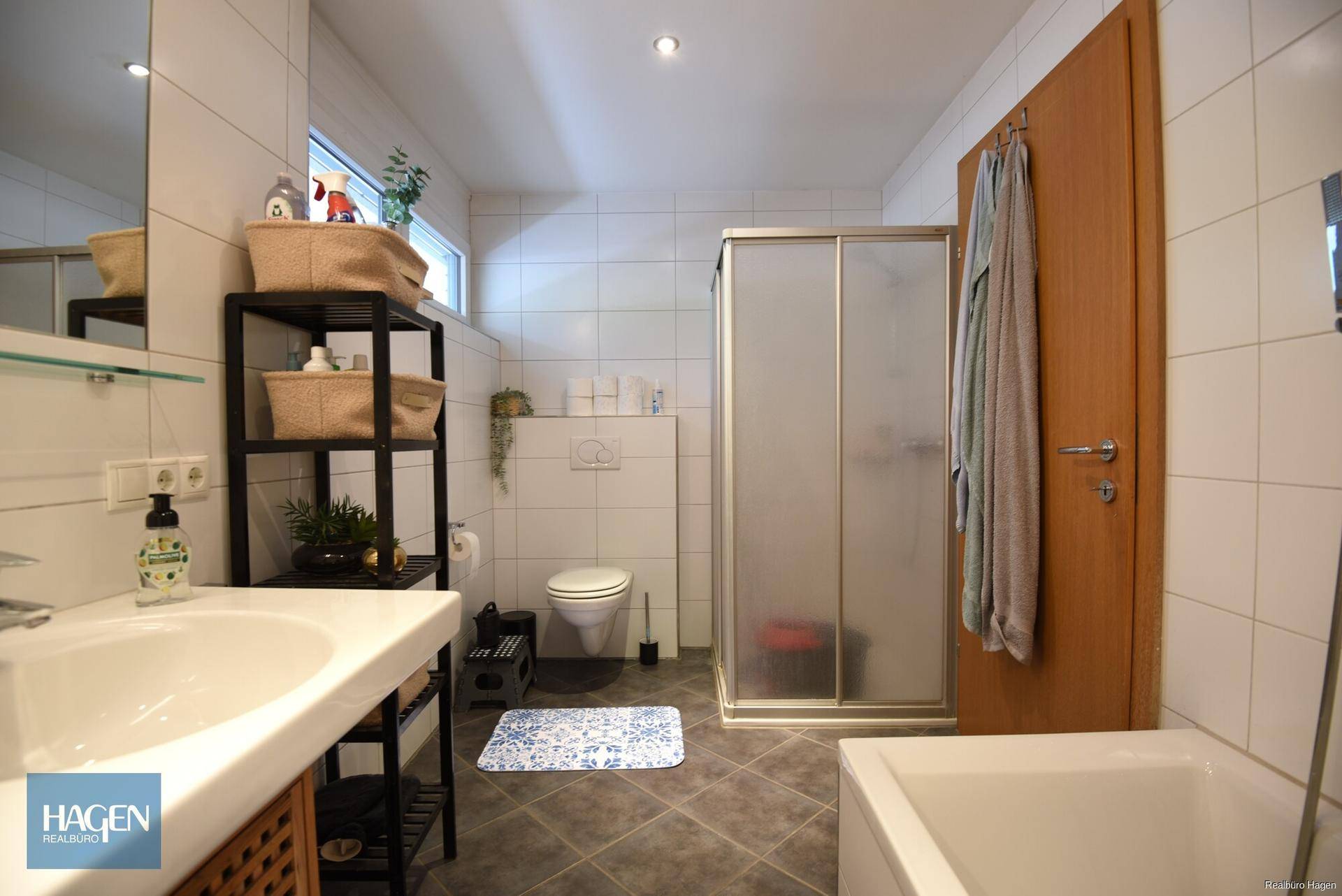 Badezimmer mit Badewanne, Duschkabine, WC und Fenster für natürliche Belüftung.