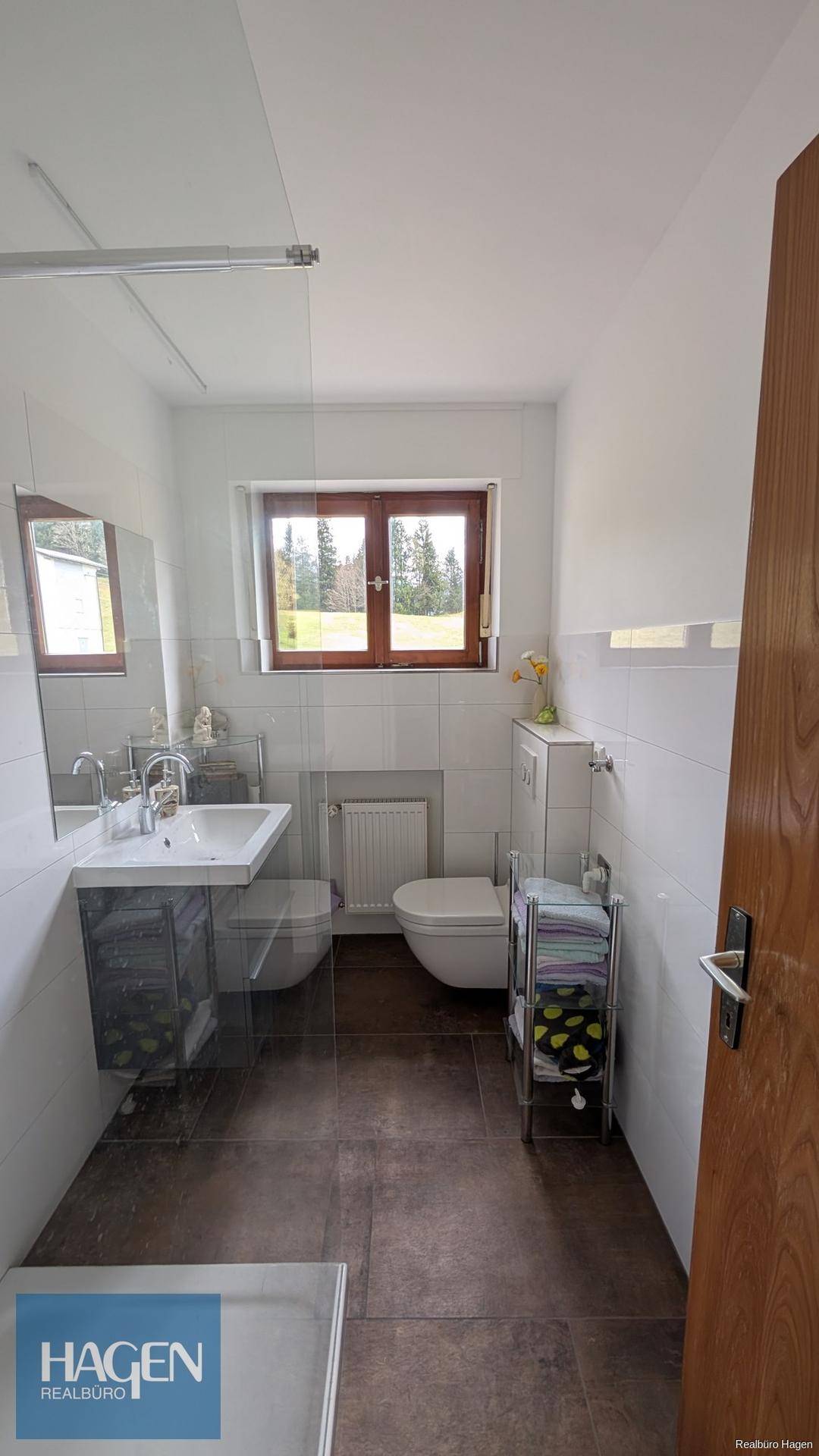 Modernes Badezimmer mit Dusche, WC, Waschbecken und Fenster für Tageslicht und Belüftung.