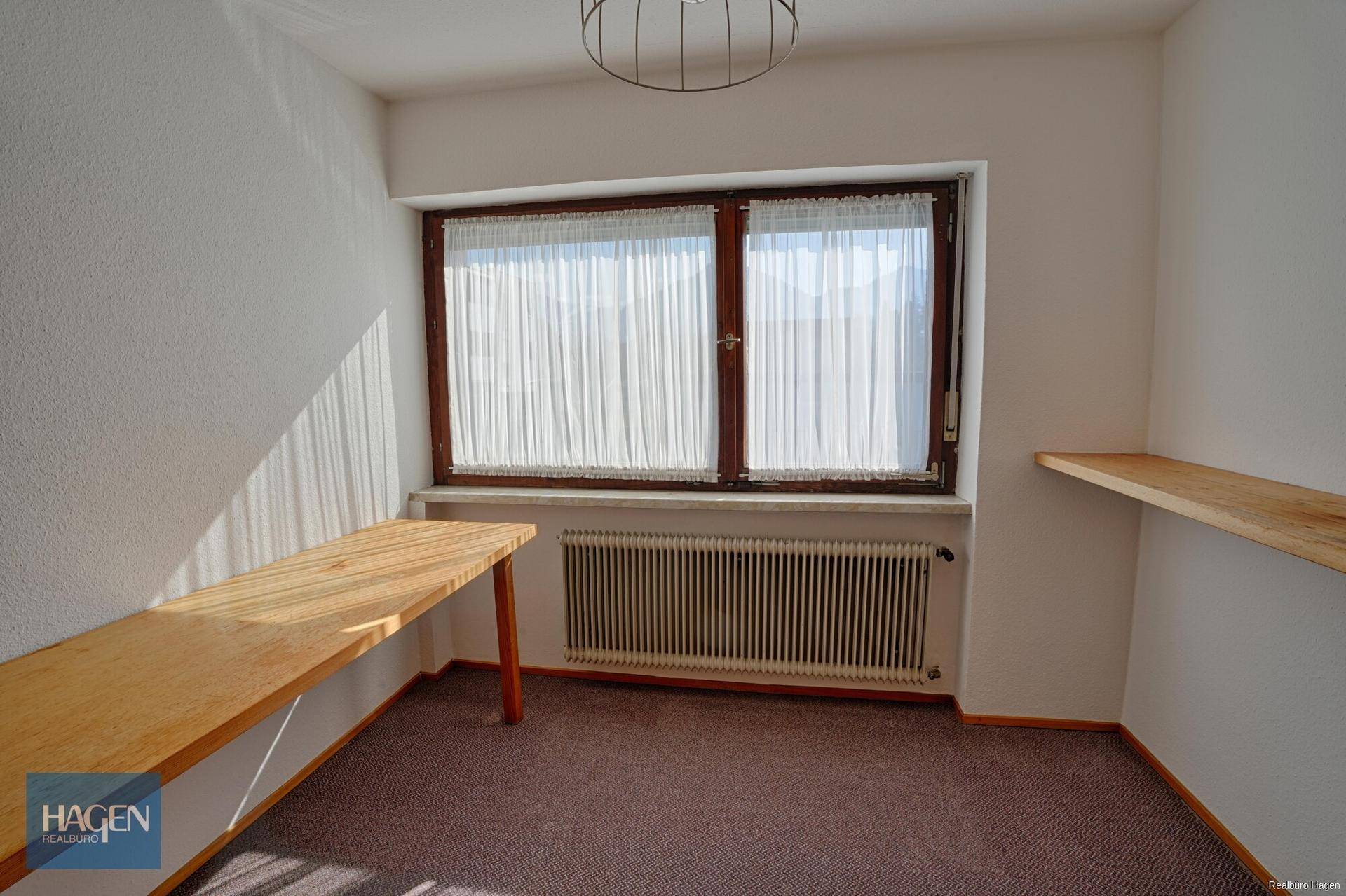 Helles Zimmer mit Holzregal und Schreibtisch, ideal als Arbeits- oder Gästezimmer.